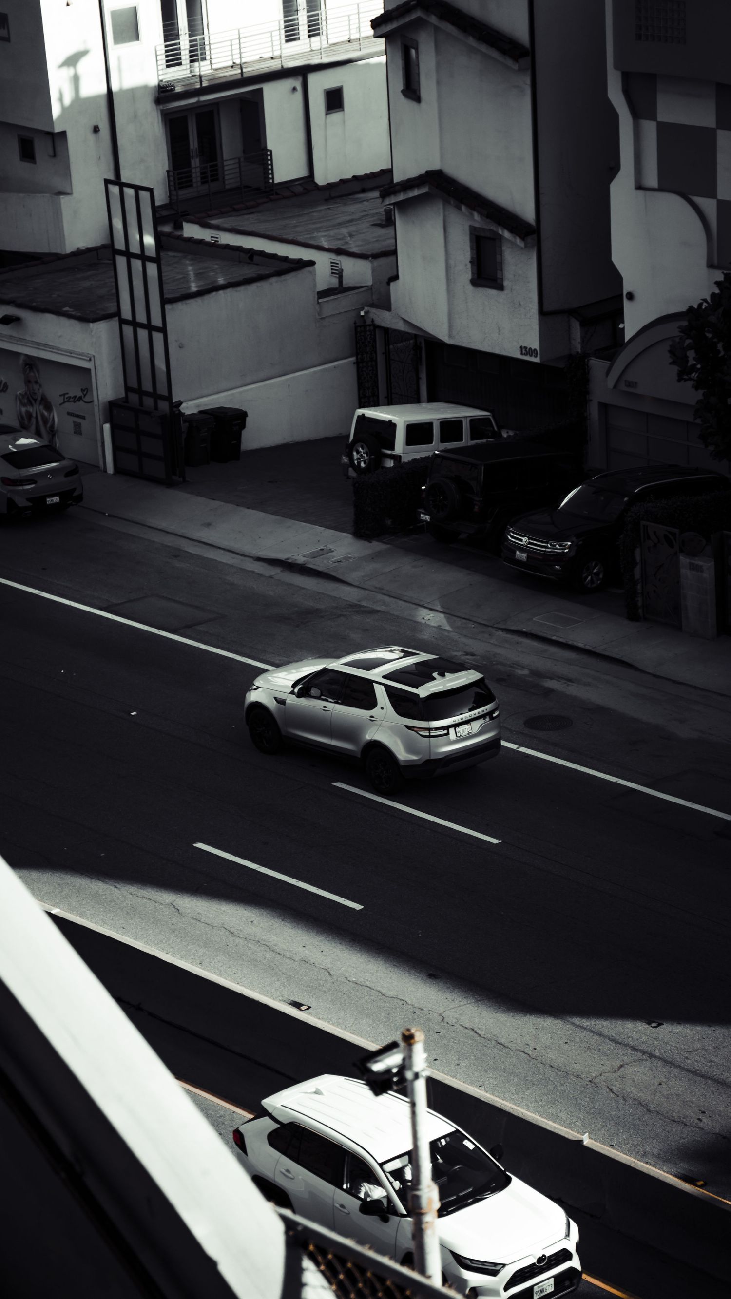 Black and white aerial view of cars parked along an urban street.