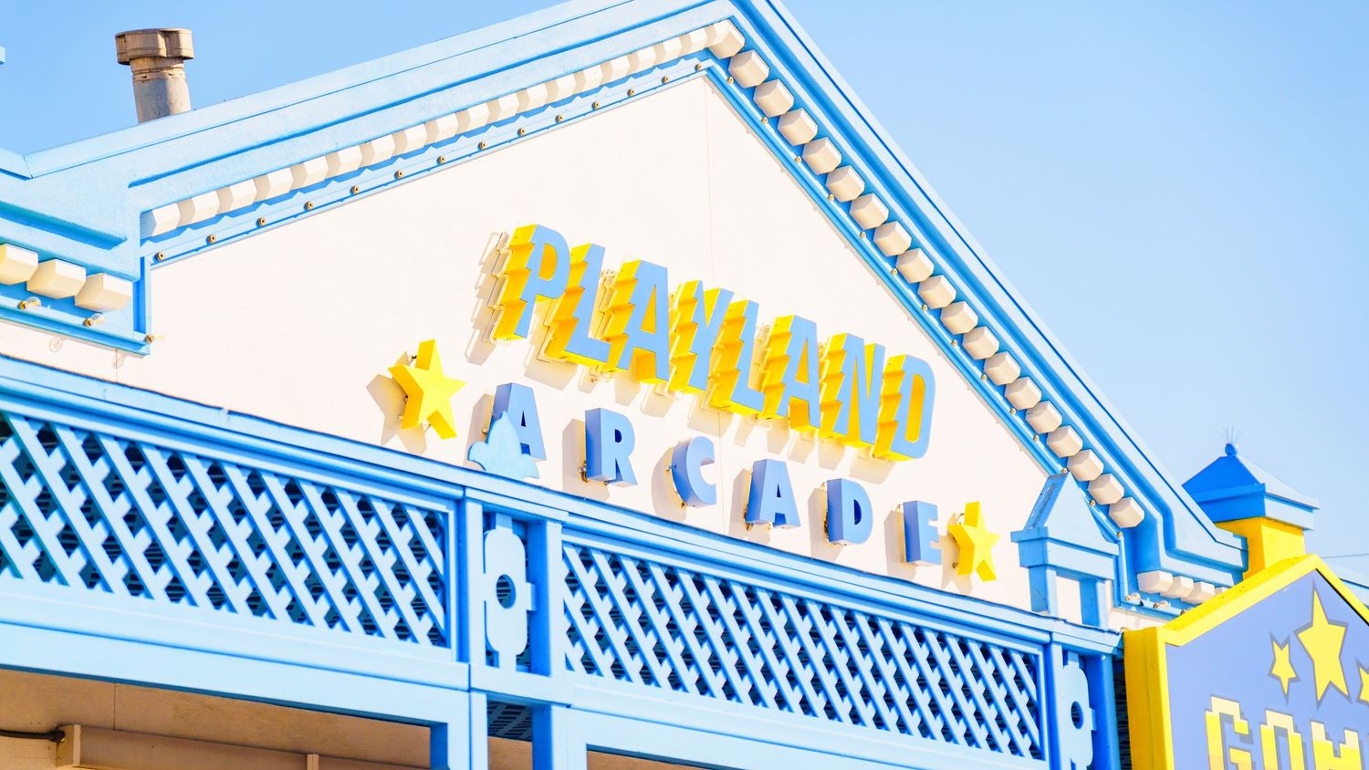 White and blue Victorian-style building facade with yellow accents and decorative lattice trim.