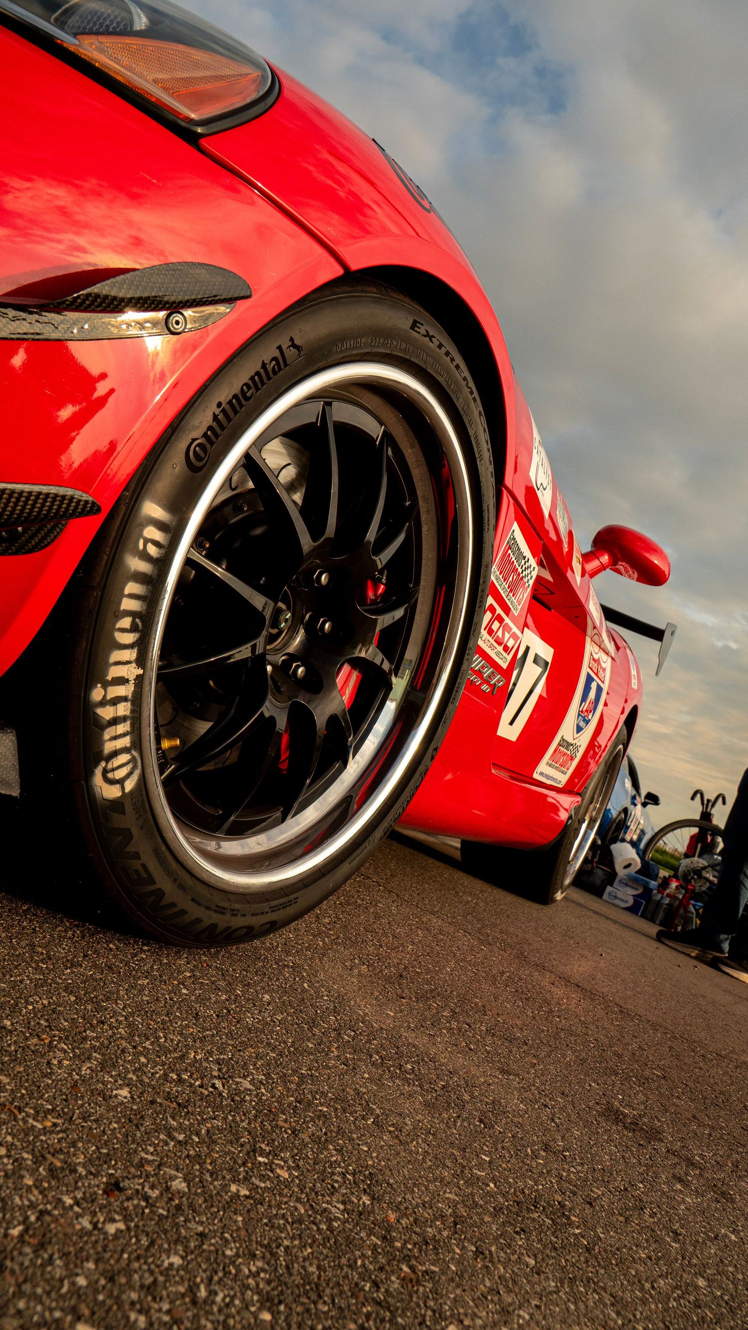 Close-up of red sports car wheel with Continental tire and black multi-spoke rim.
