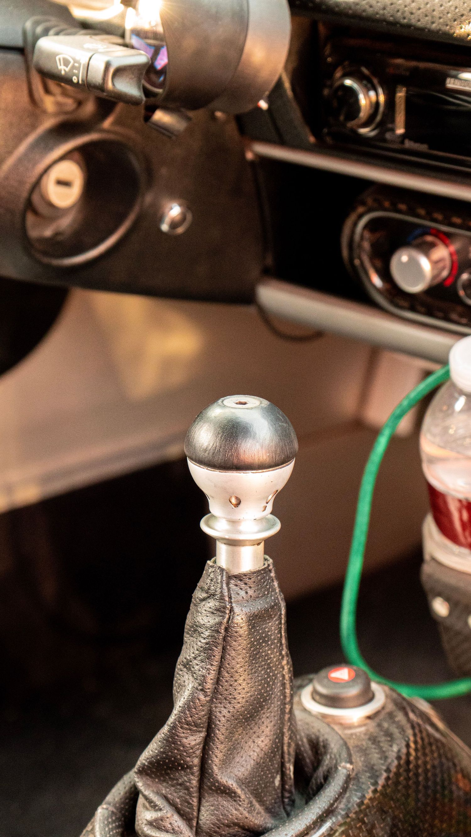 Close-up of metal gear shifter knob in carbon fiber textured console.