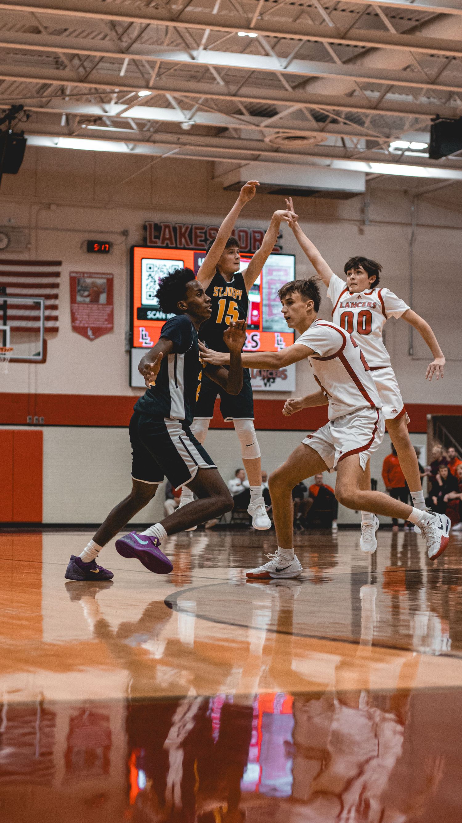 Low angle shot of basketball players in motion on a polished gymnasium floor.