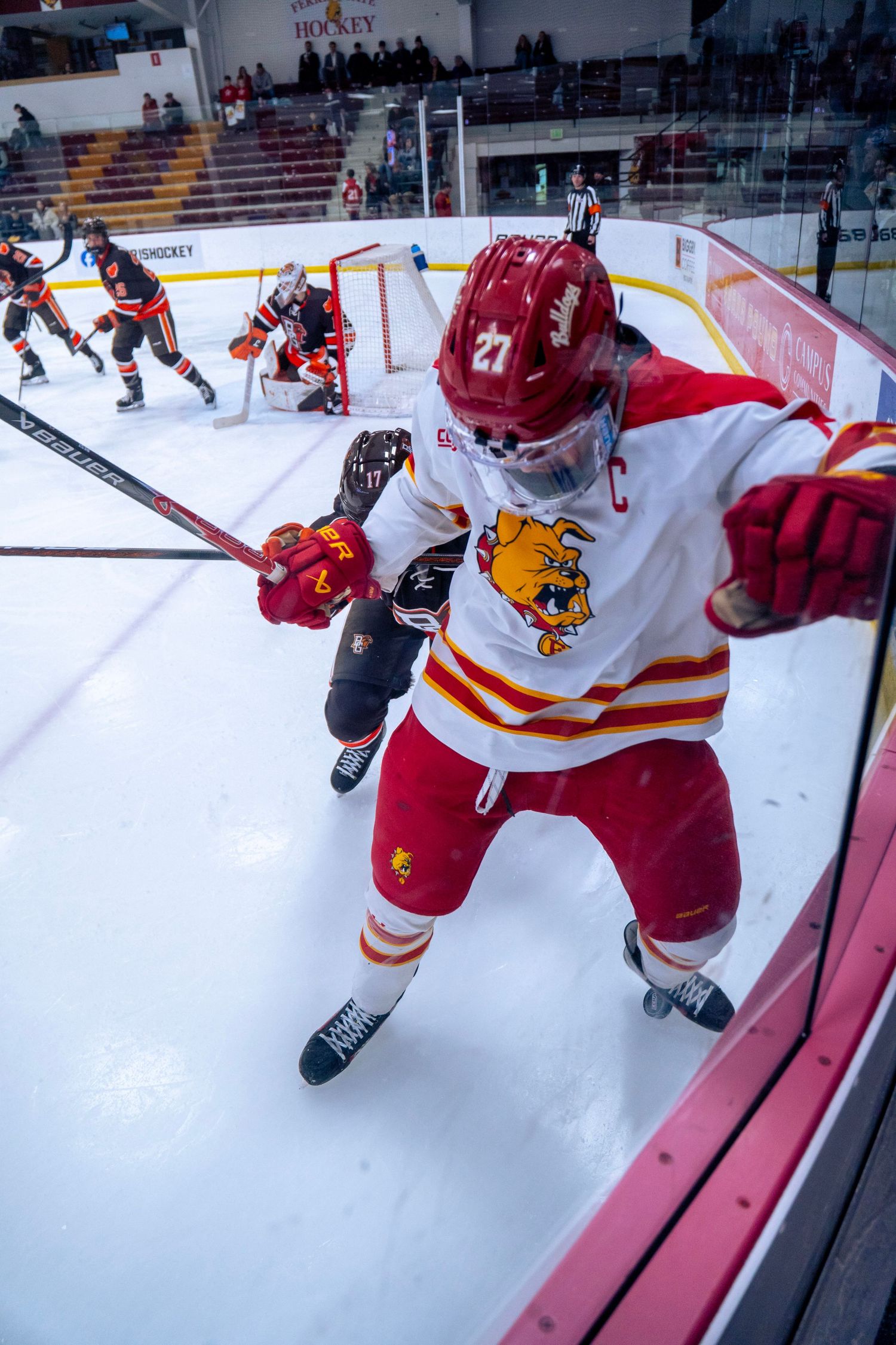 Hockey player in red and white jersey checks opponent against boards during competitive ice hockey game.