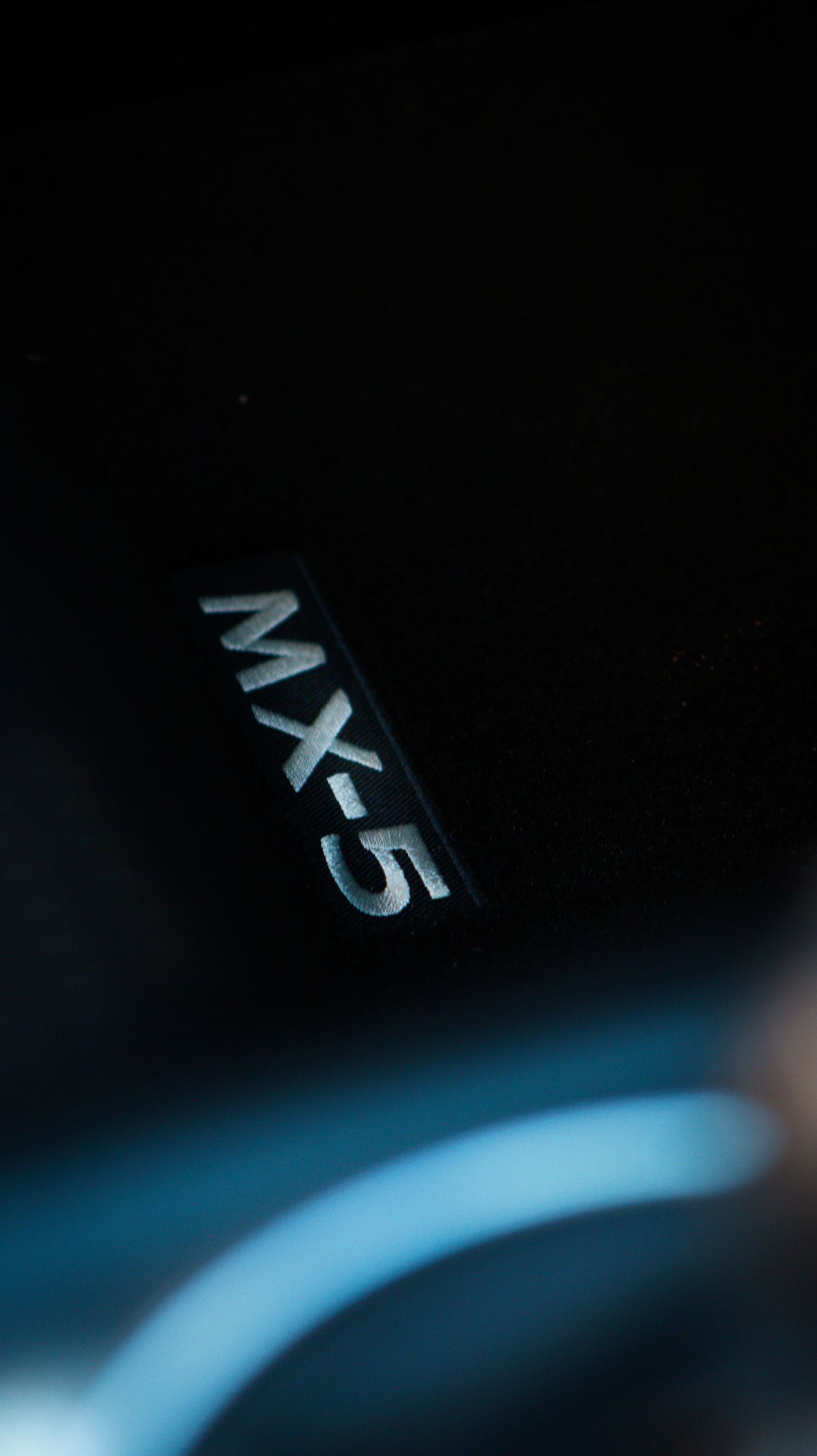 Macro shot of MX-5 badge in dark lighting conditions.