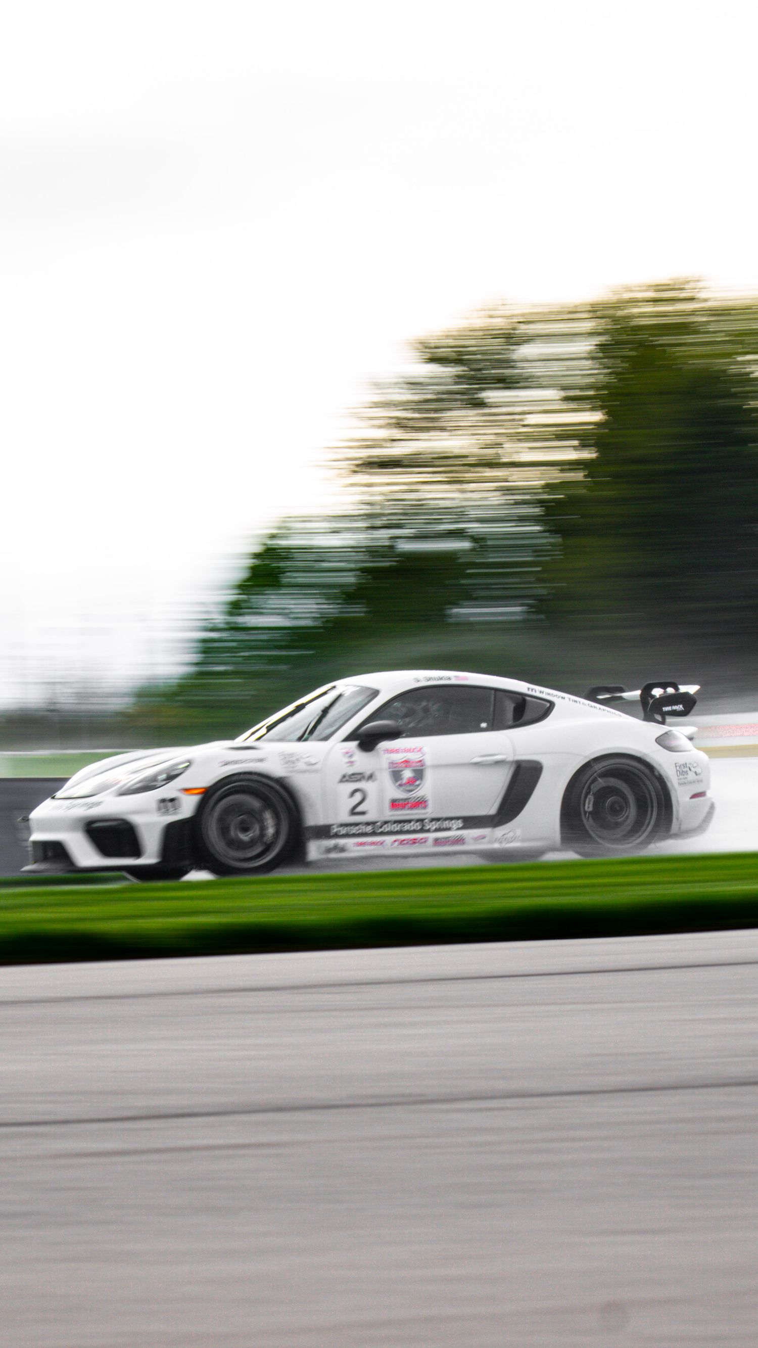 White Porsche race cars in formation during track competition.