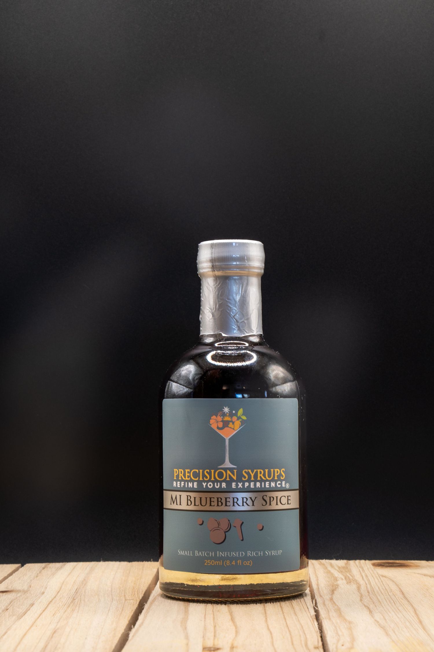 Artisanal cocktail mixer bottle with blueberry spice flavor against dark backdrop.