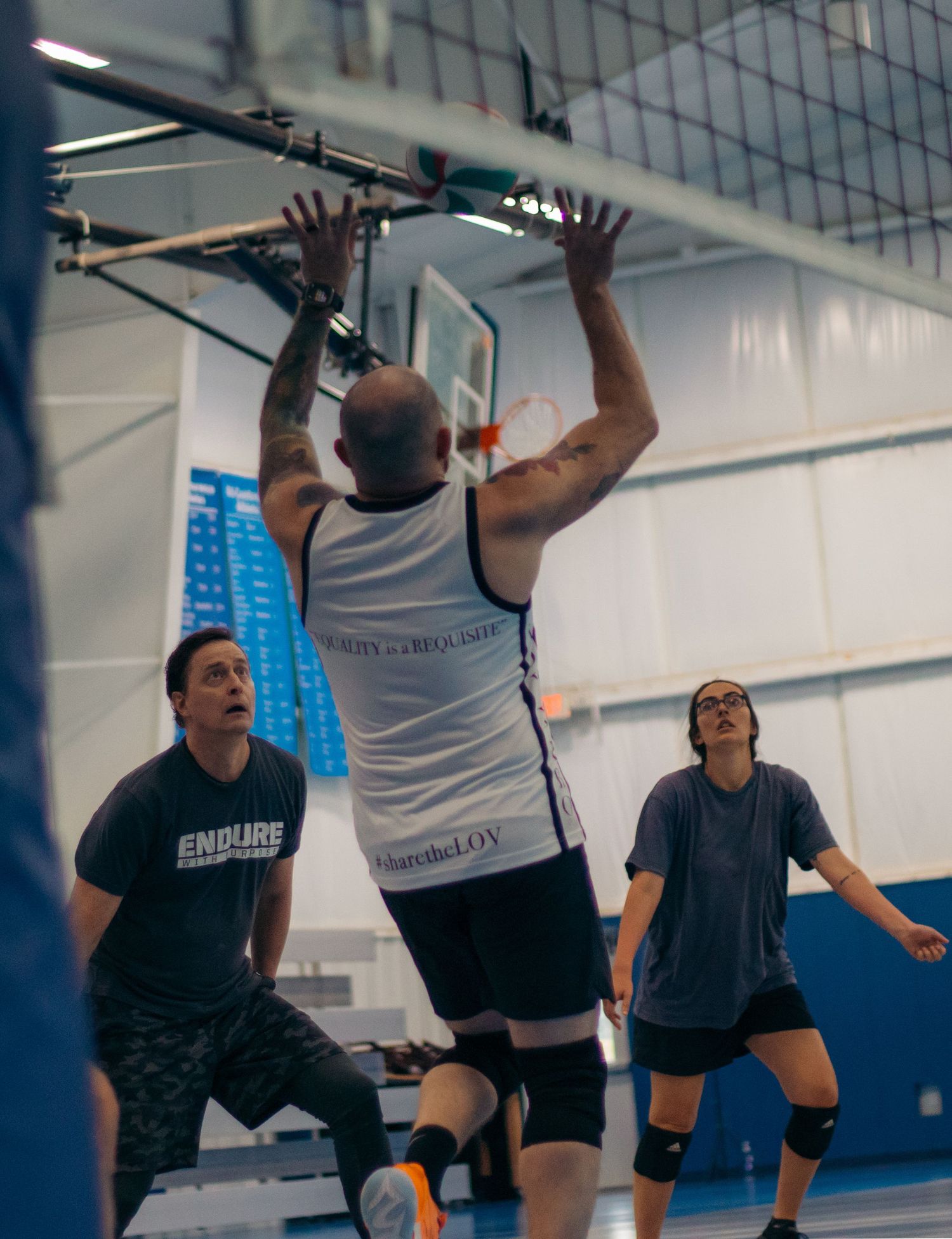Players position themselves at net during competitive indoor volleyball match.