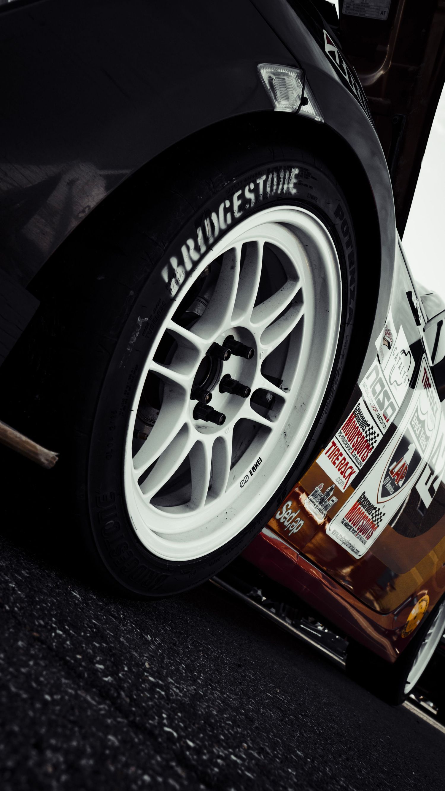 Close-up view of a white Bridgestone racing wheel mounted on a black vehicle.