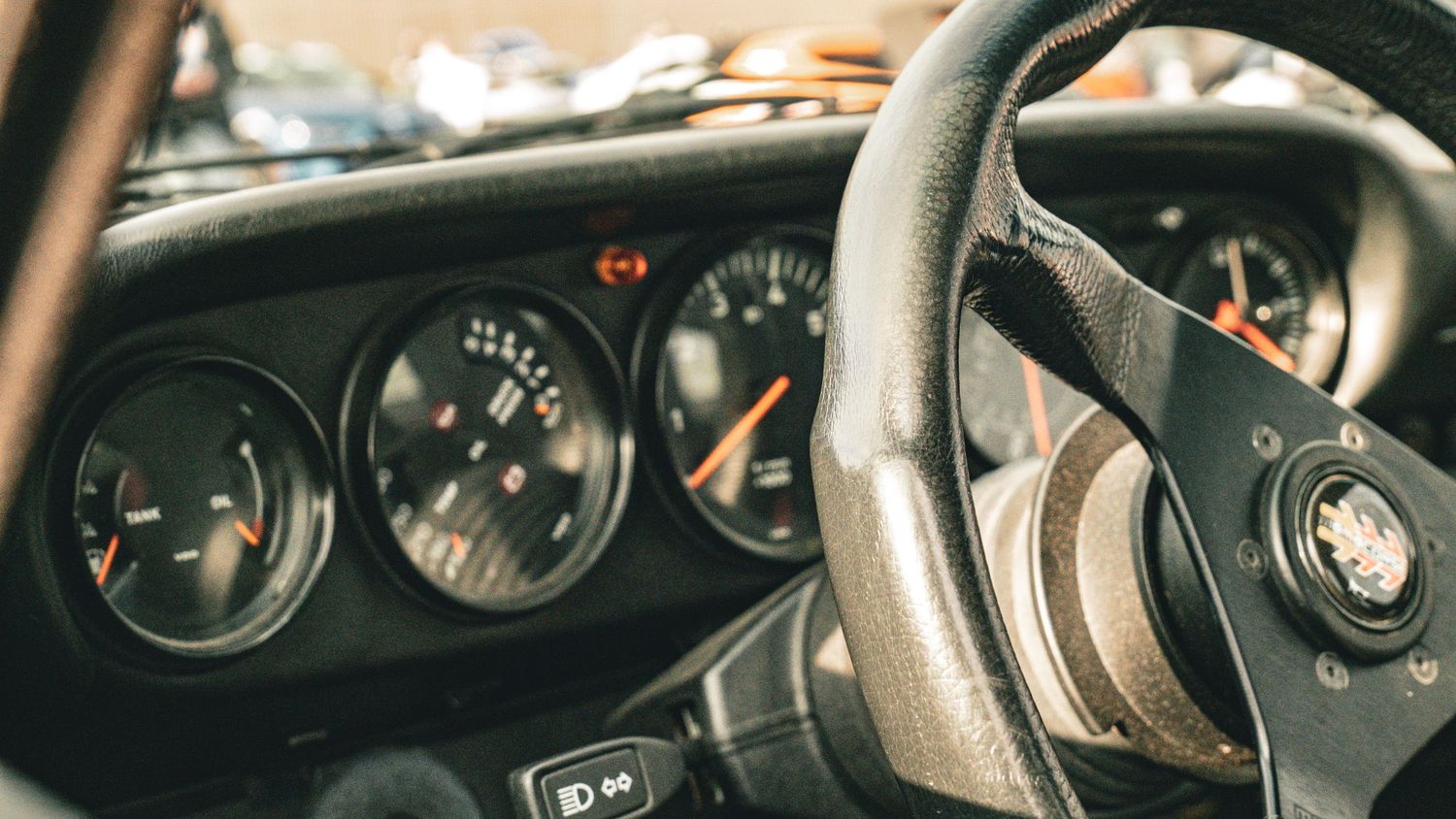 Classic sports car dashboard showing analog gauges and steering wheel.
