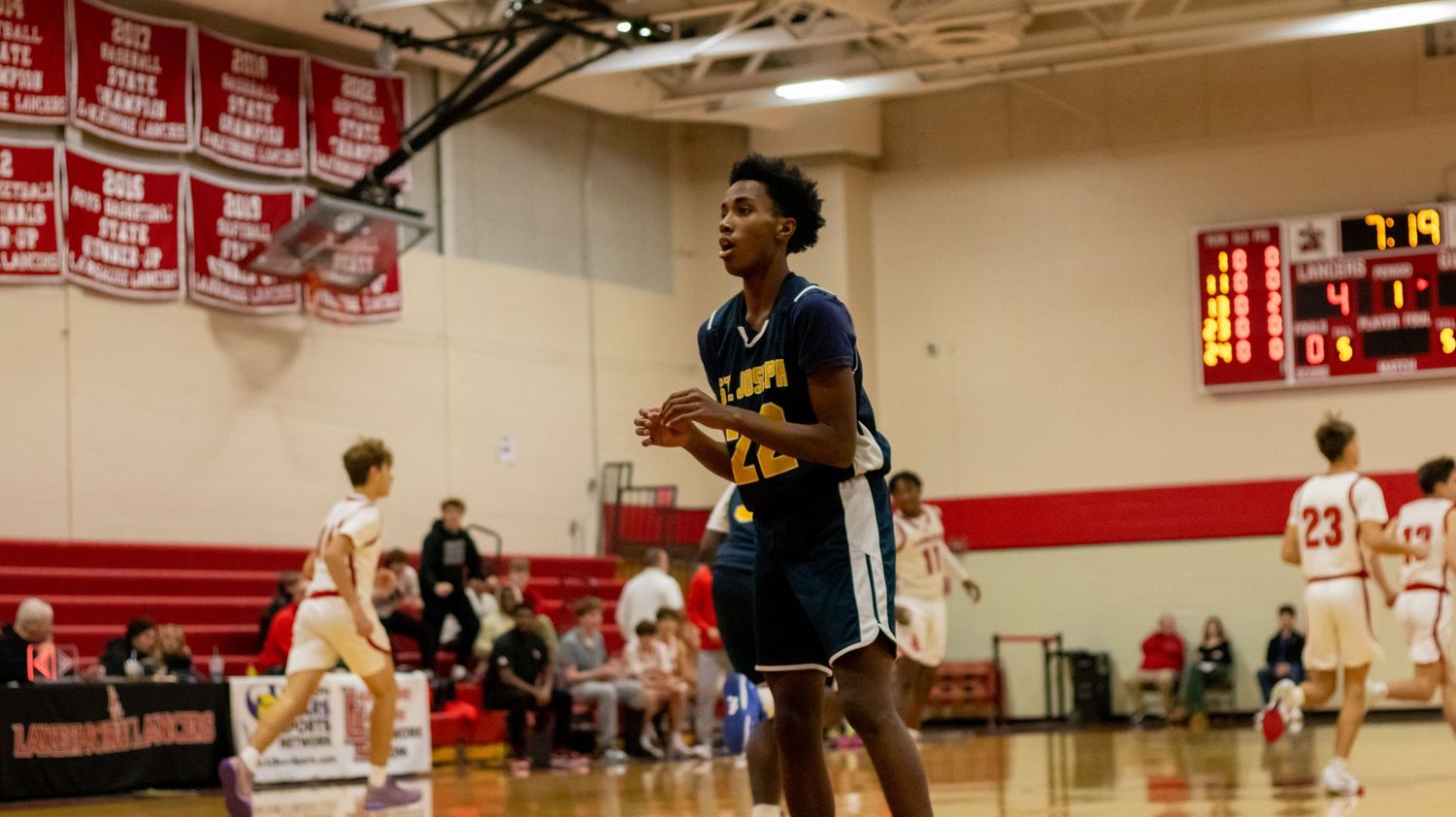 Basketball player dribbles on court during competitive high school game.
