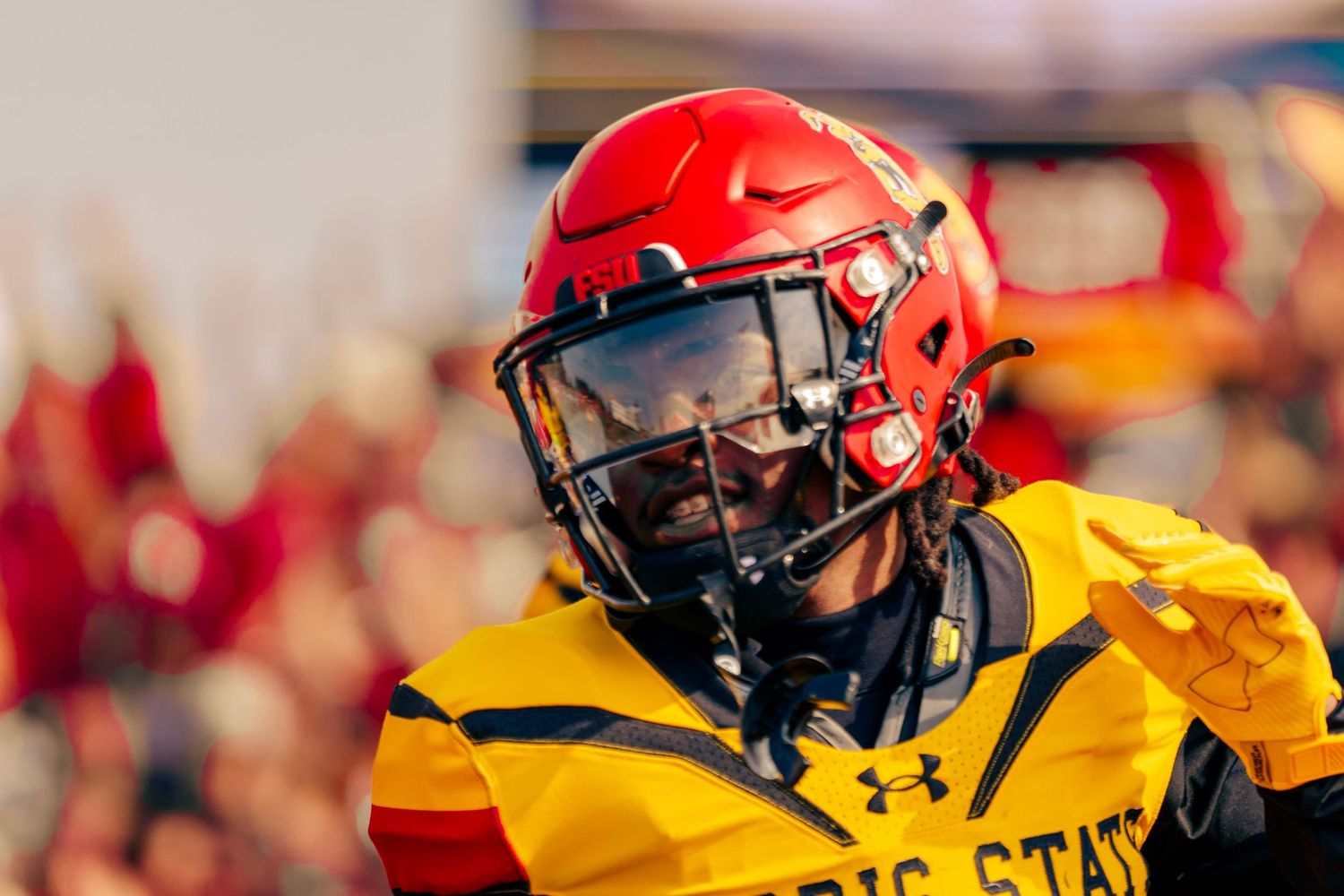 Football players in red and yellow uniforms line up on the field during a competitive game.