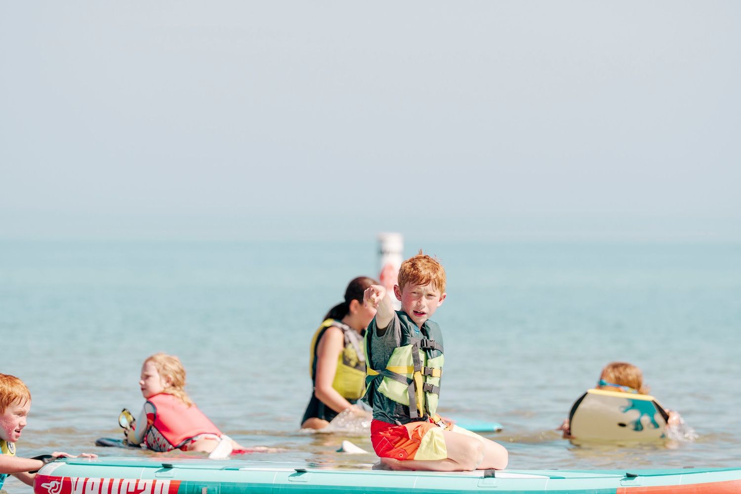 People enjoying paddle board yoga class in calm turquoise waters on a sunny day.