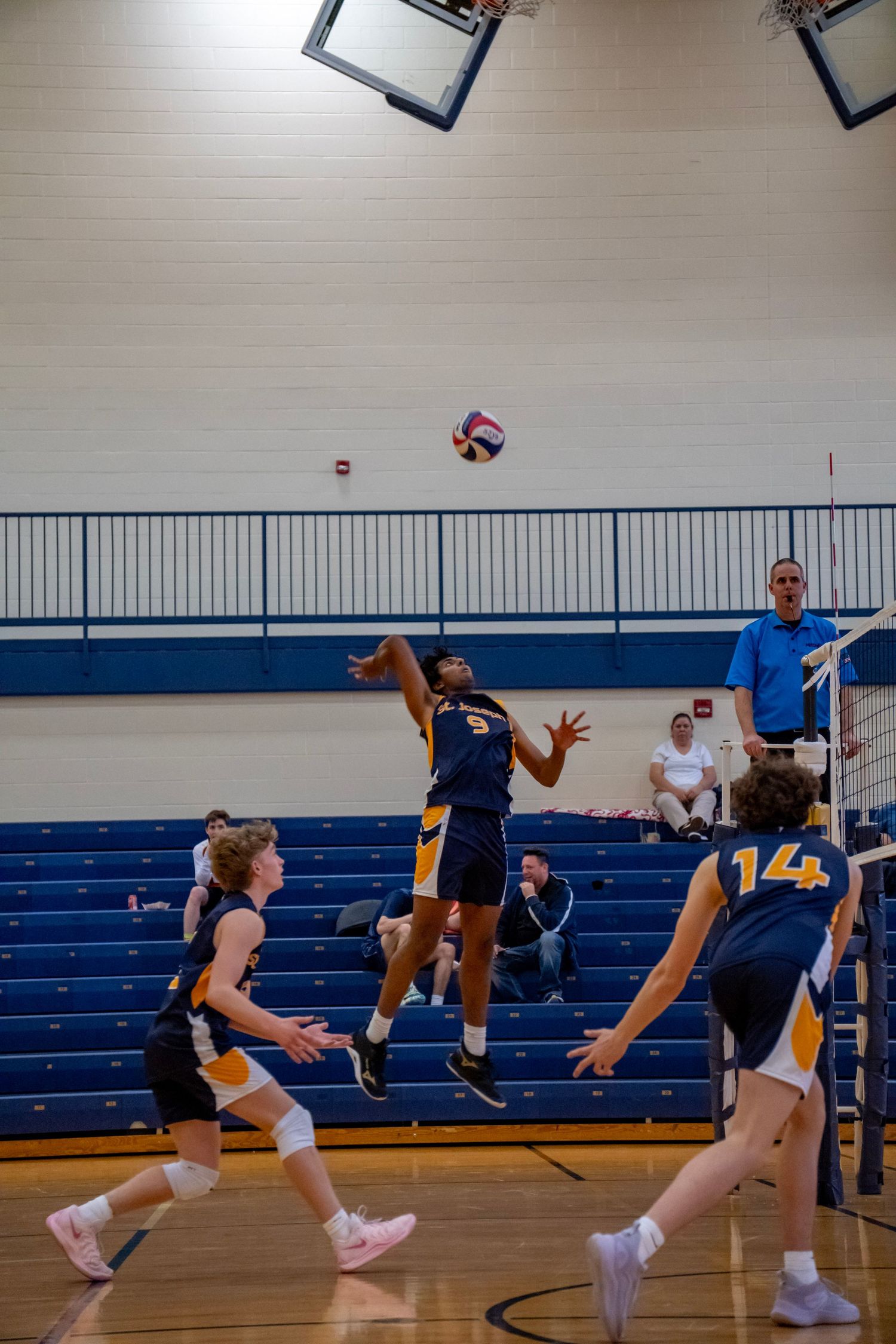 Volleyball player leaping high to spike the ball during an indoor game.