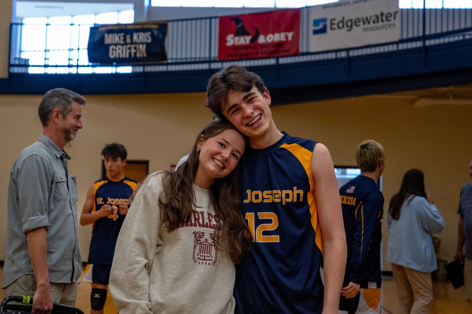 Students gathered in a school gymnasium with sports banners on the walls.