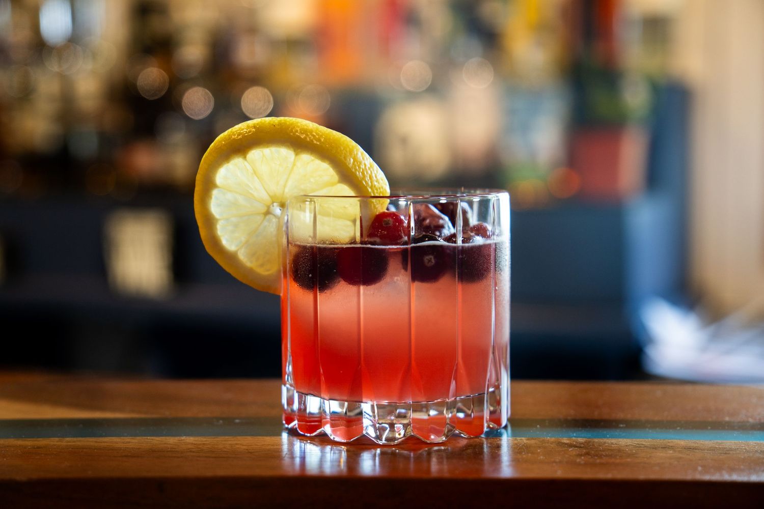 A classic cocktail with citrus garnish served in an elegant crystal coupe glass on a bar top.