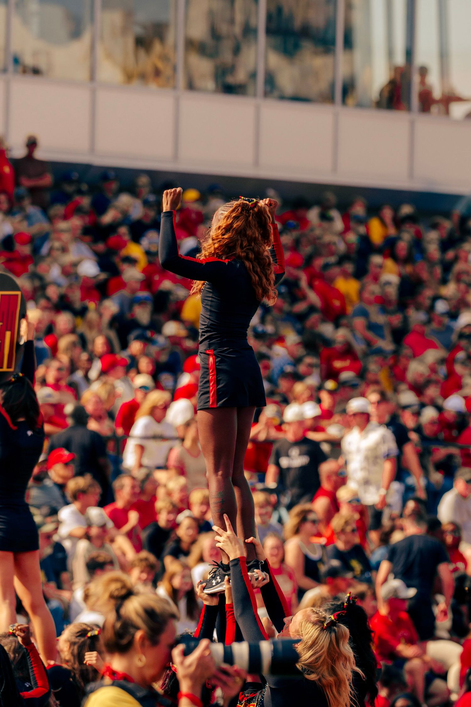 Excited fans raise their phones and cameras to capture a moment during a crowded sporting event with red-clad spectators.