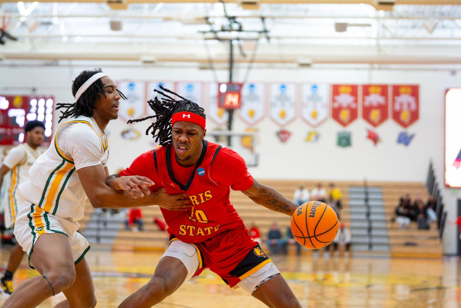 Basketball players compete for possession during an intense game on a gymnasium court.