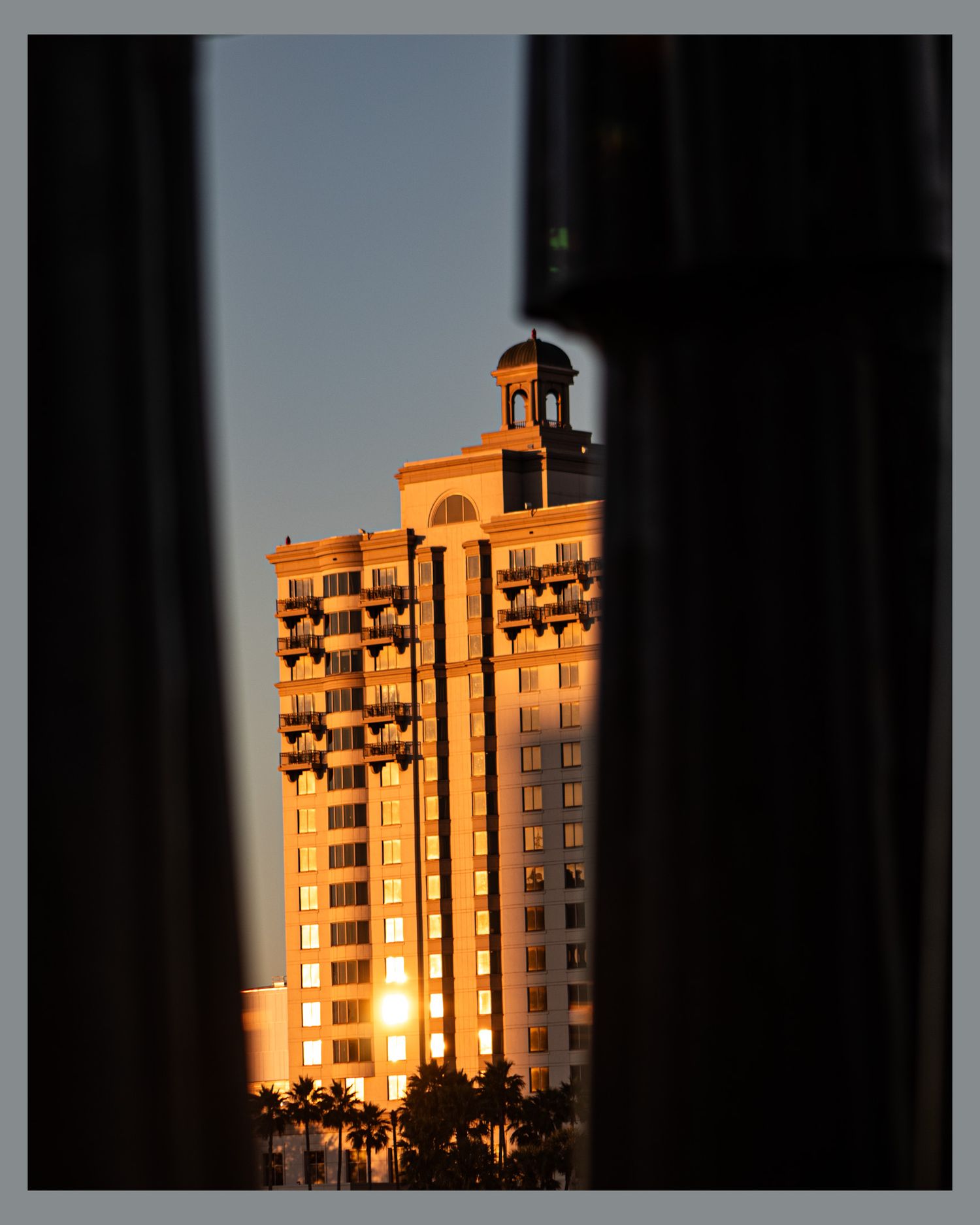 Golden sunlight illuminates tall hotel building with ornate architectural details at sunset.