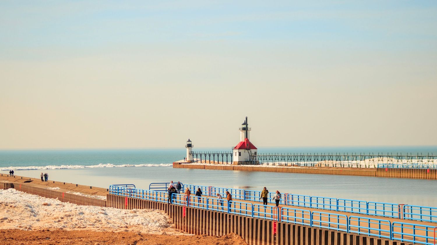 St. Joseph lighthouse and pier on Lake Michigan with beach in foreground.