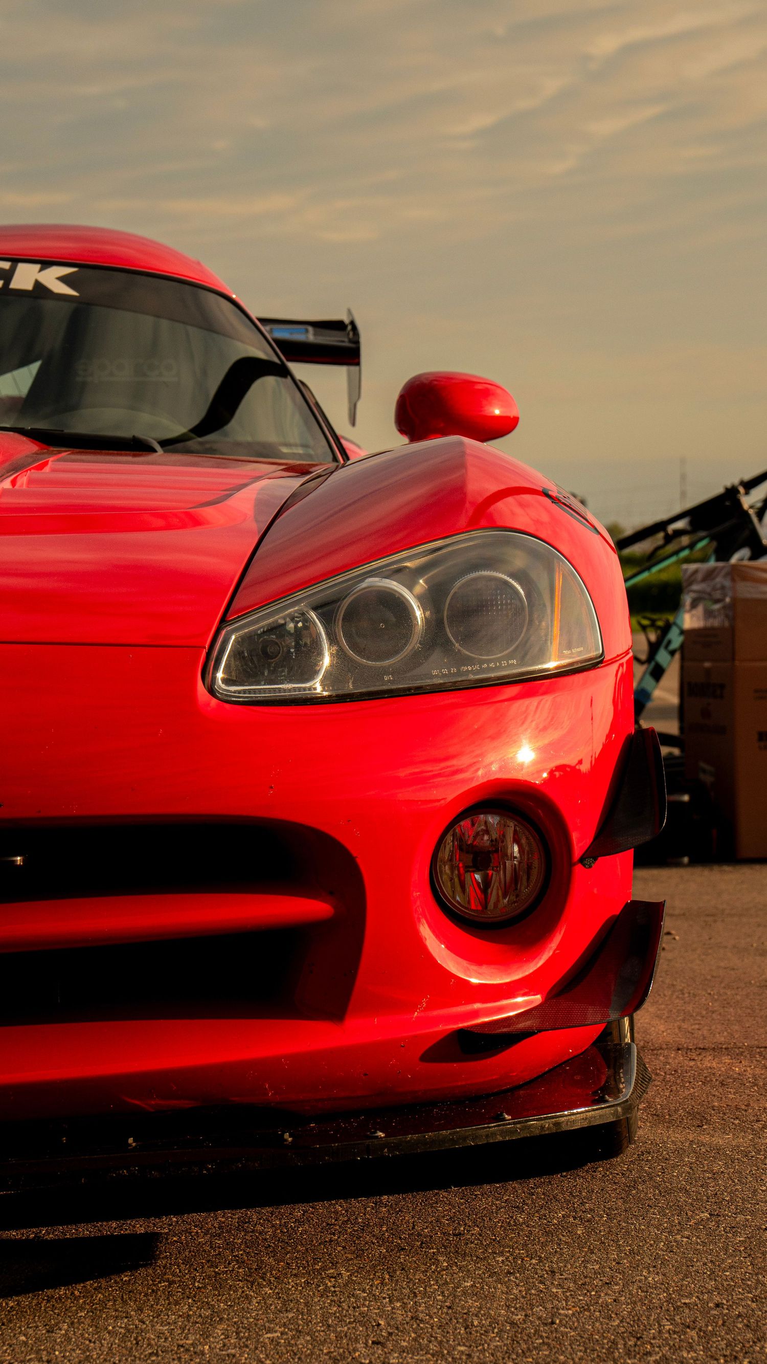 Close-up of red Dodge Viper front end showing headlight and fog light details at sunset.