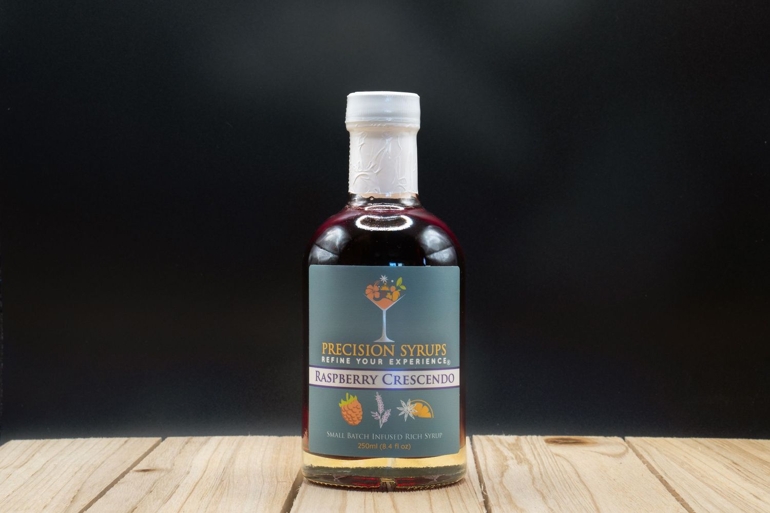Dark spirits bottle with white cap and tree emblem displayed on wooden surface against black backdrop.