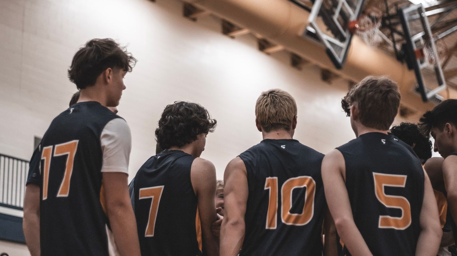 Back view of volleyball team players showing jersey numbers 17, 7, 10 and 5.