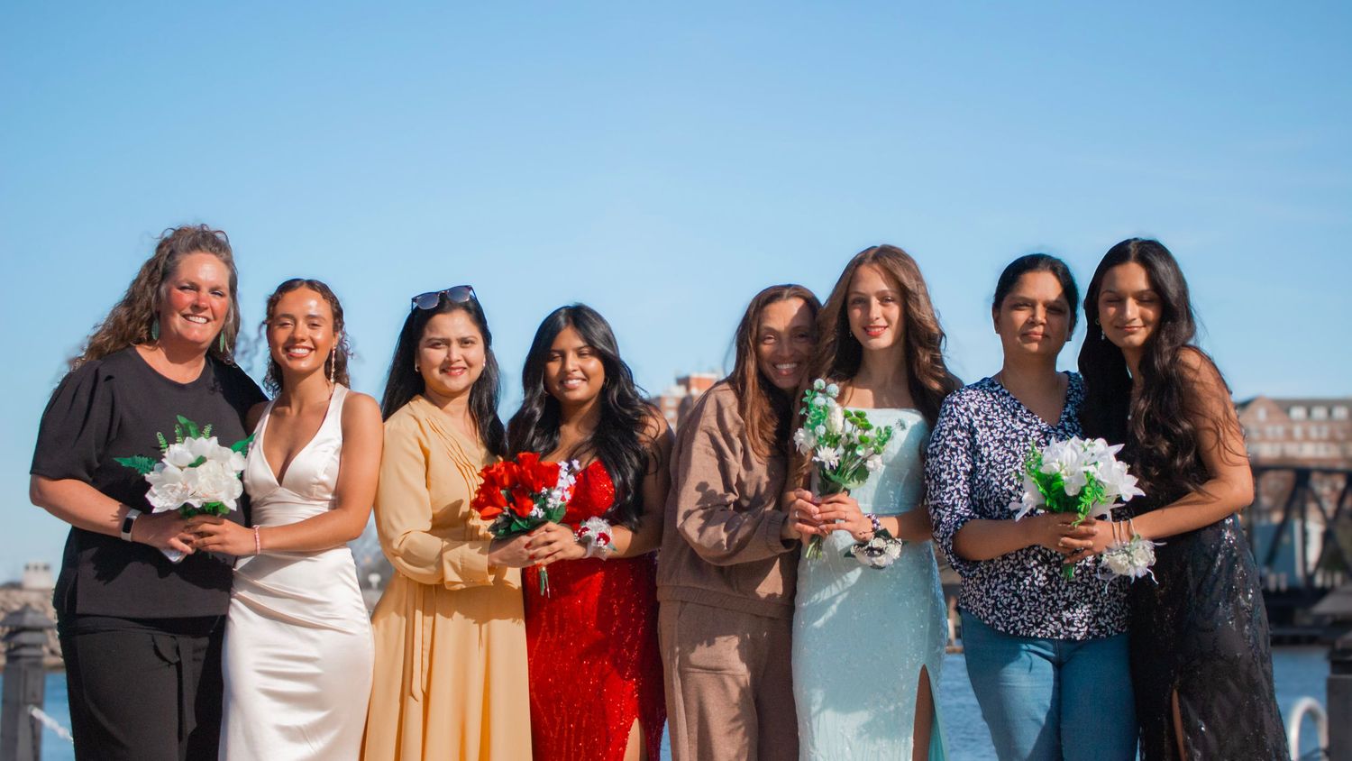 A long horizontal photo collage showing a group of people posing together outdoors against a blue sky.