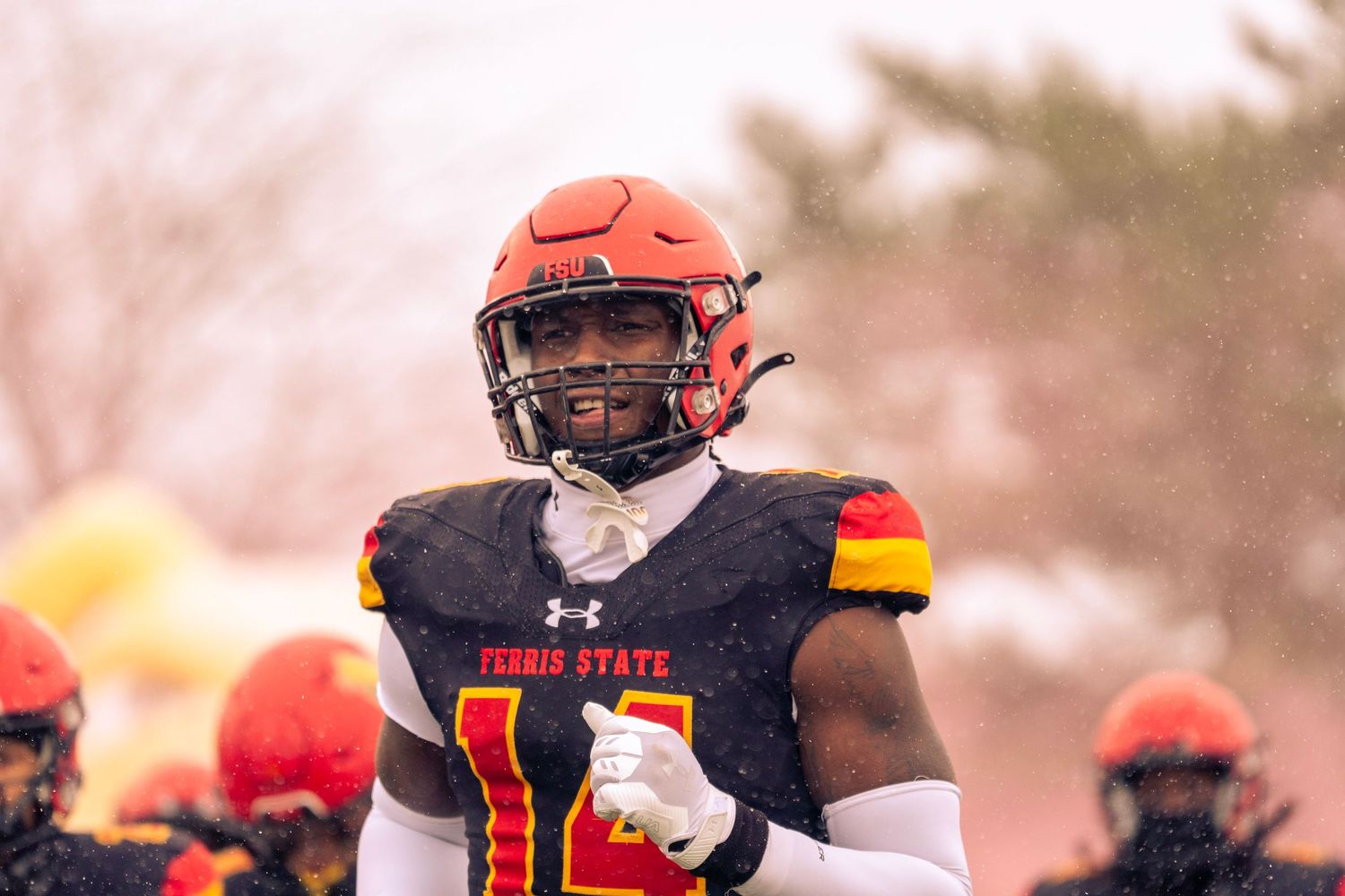College football players in orange jerseys and black helmets huddle together during a game.
