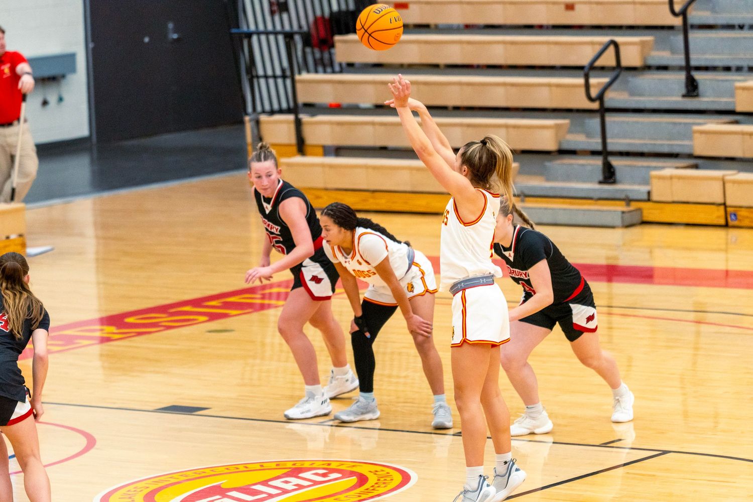 Volleyball players practicing drills and warming up on a gymnasium court with red lines.