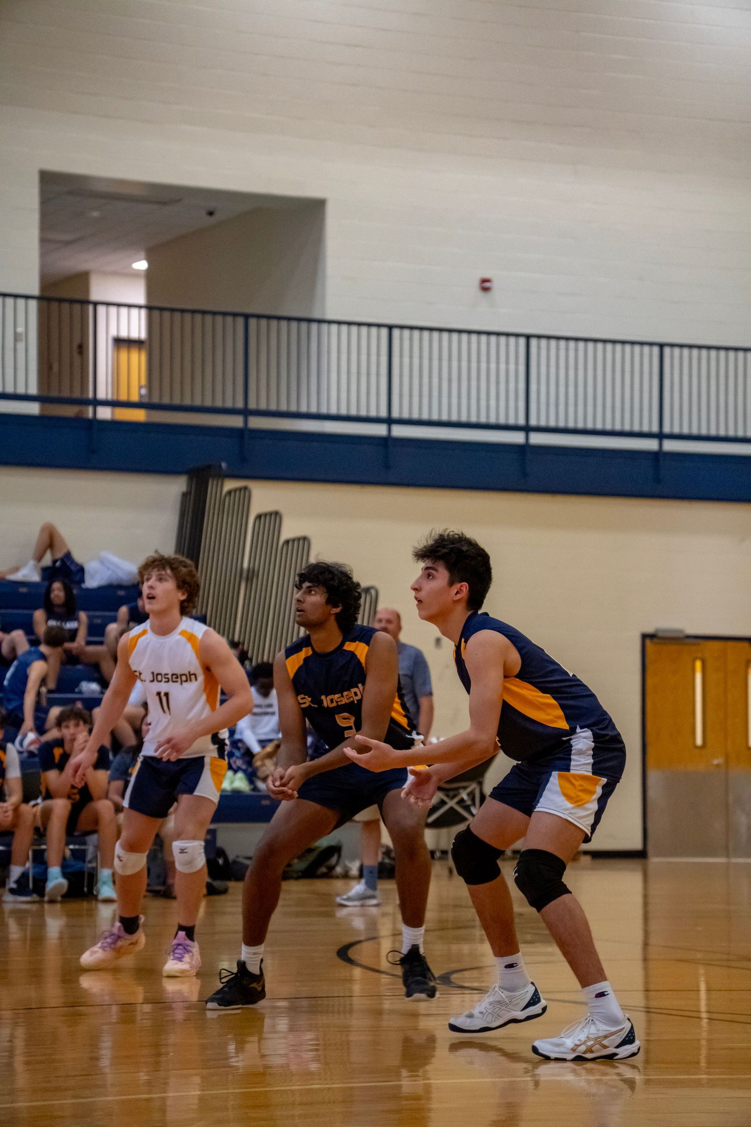 Players from opposing teams line up in defensive positions during volleyball match.