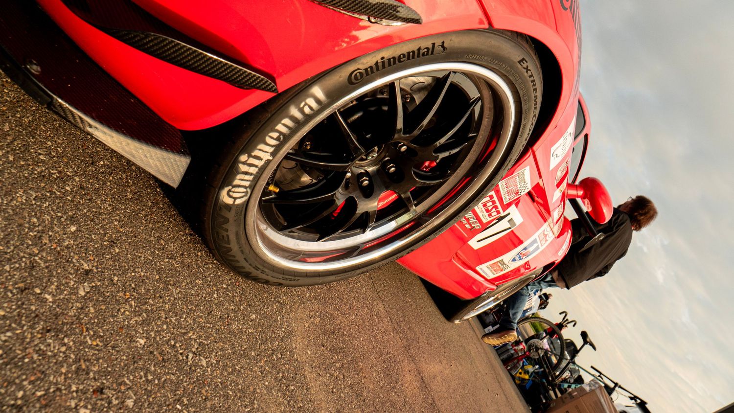 Low angle view of red race car wheel with Continental tire and black racing rim.