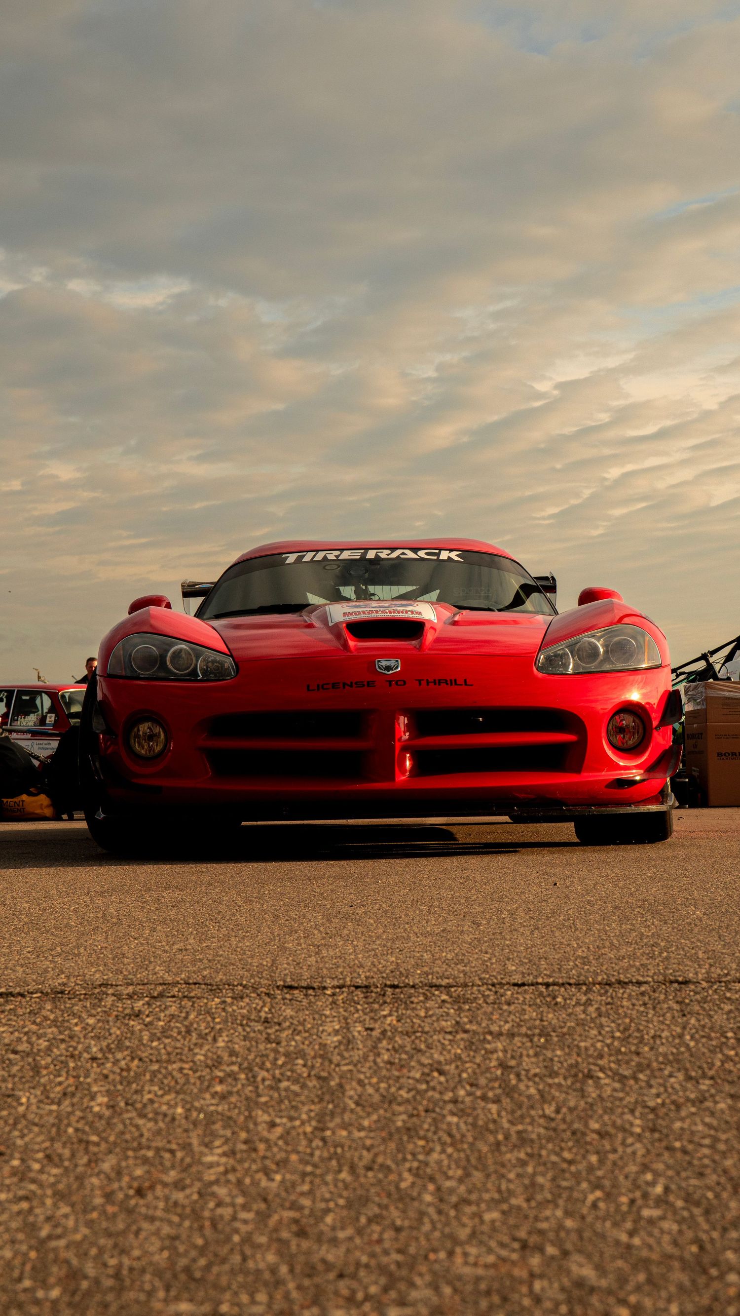 Low angle front view of red Dodge Viper against dramatic cloudy sunset sky.