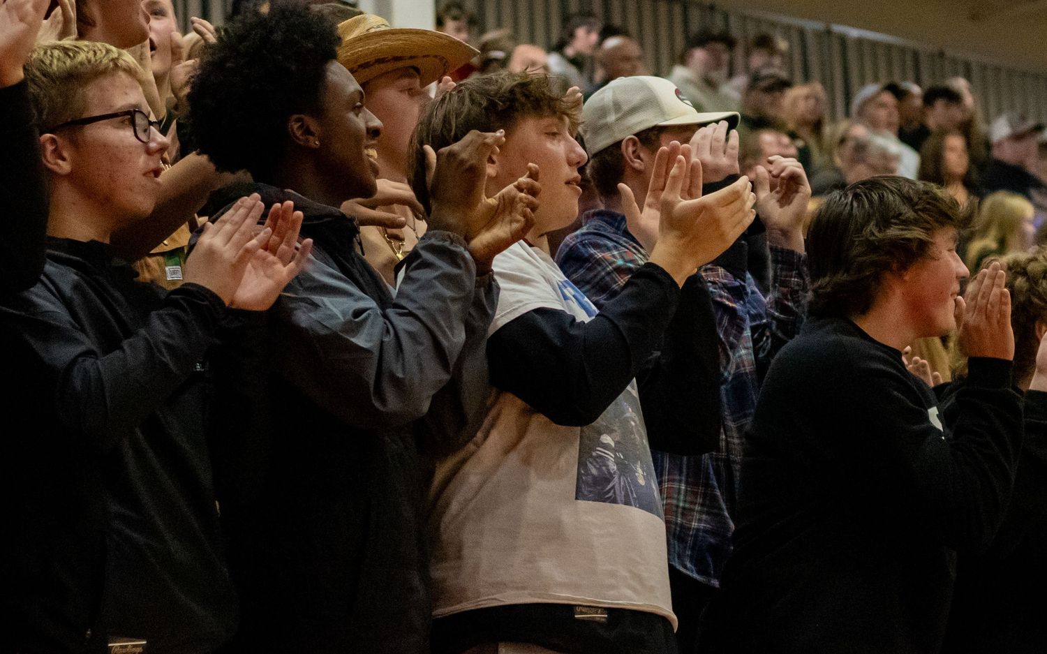 Spectators watch intently from bleachers during a basketball game.