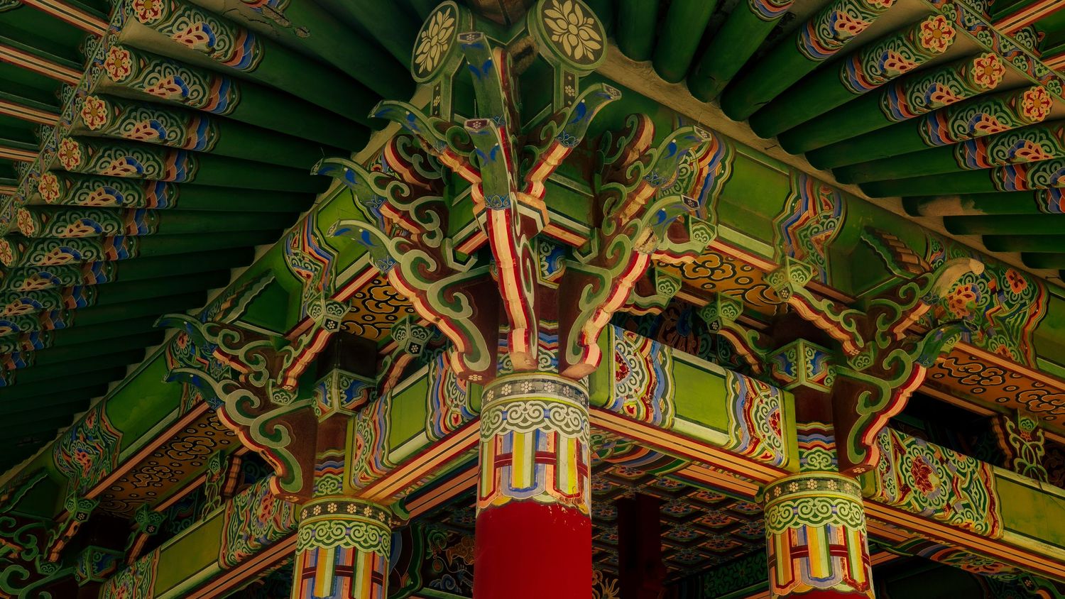 Intricate green and gold painted ceiling patterns in traditional Korean architecture.