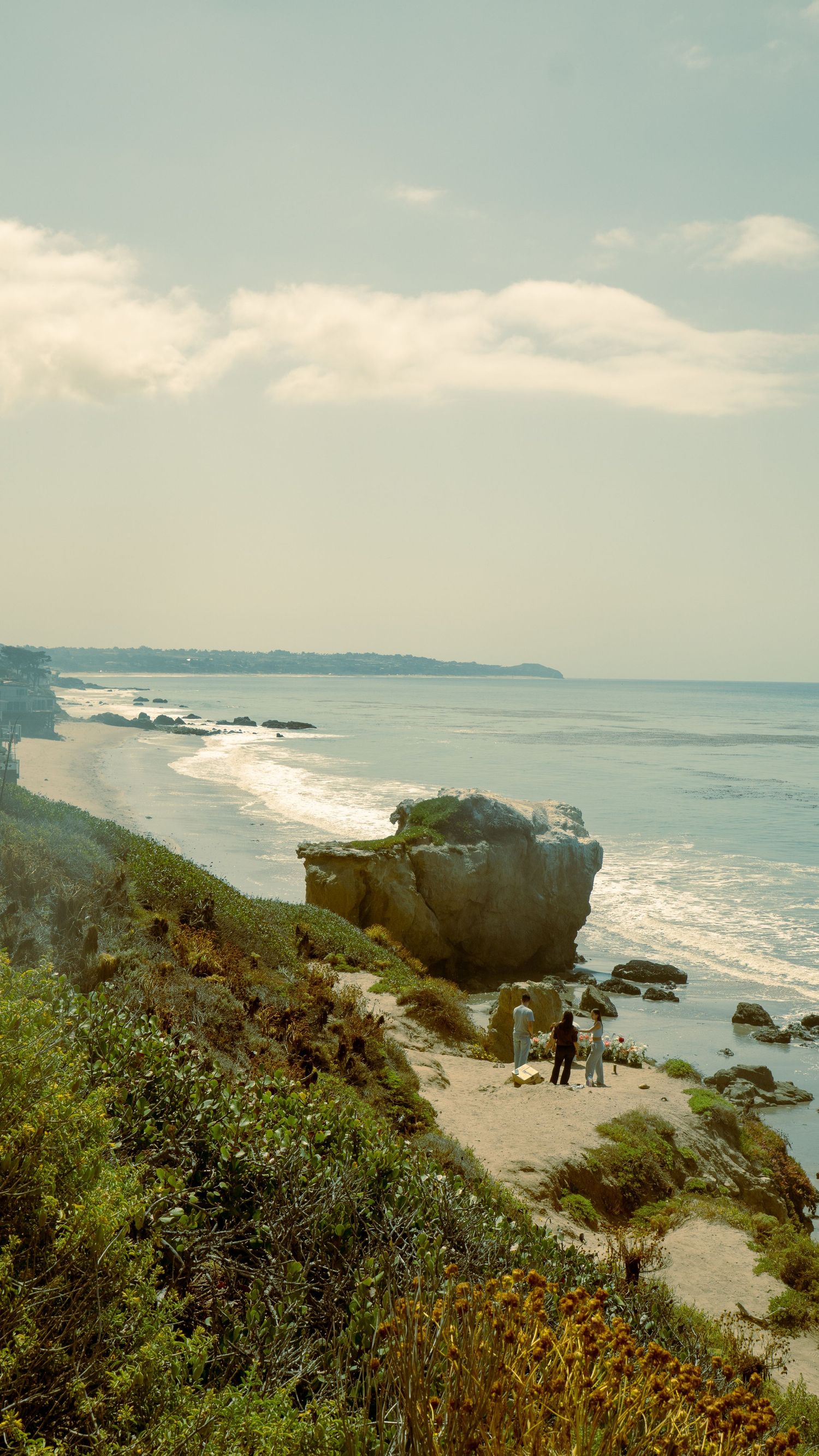 Scenic coastal view with large rock formations and beach path along California coastline.