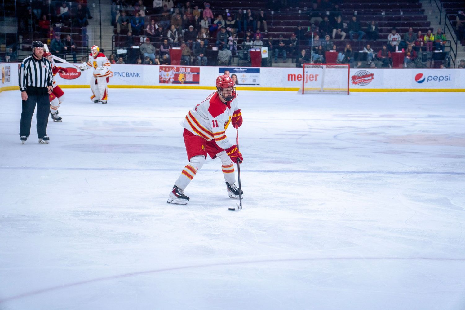 Hockey players compete for the puck during an intense professional ice hockey match on a brightly lit rink.