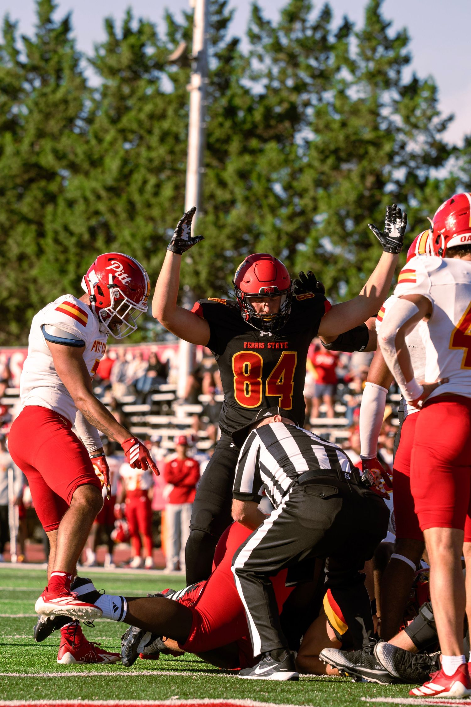 Football players collide at the line of scrimmage during an intense game between teams in red and black uniforms.