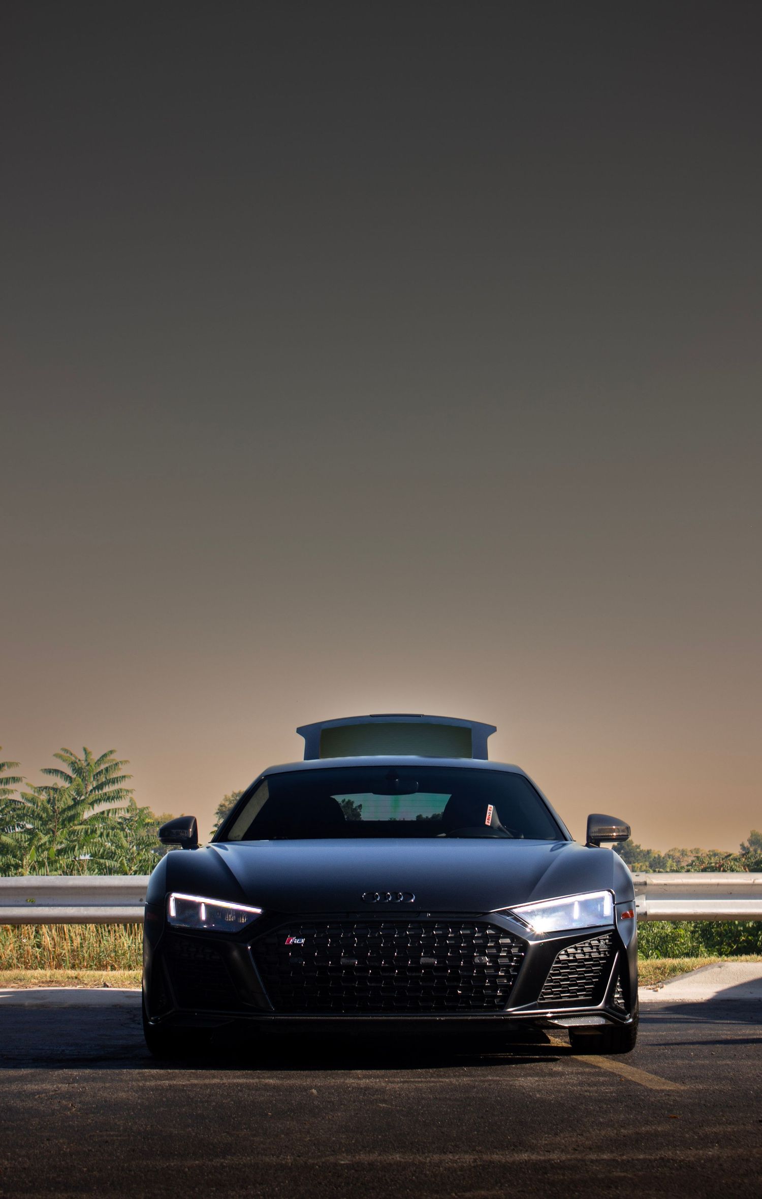 Sleek Audi R8 silhouette photographed against dark background showing distinctive LED headlights.