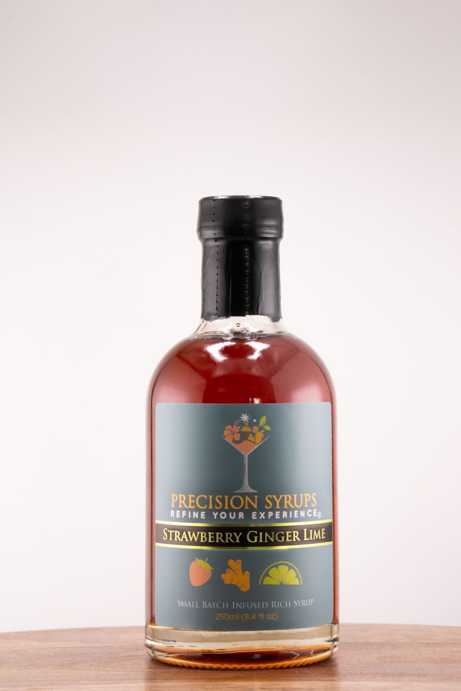 Artisanal strawberry ginger lime syrup bottle with distinctive branding on wooden table.