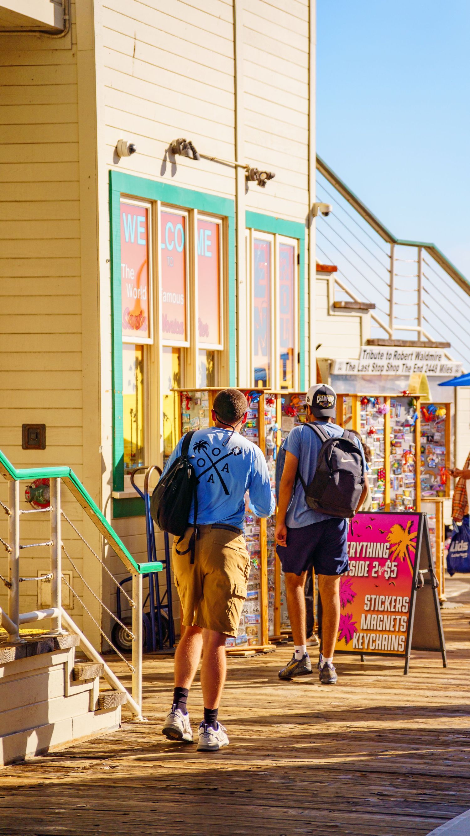 Wooden boardwalk with retail shops and display signs at a beachside amusement park.