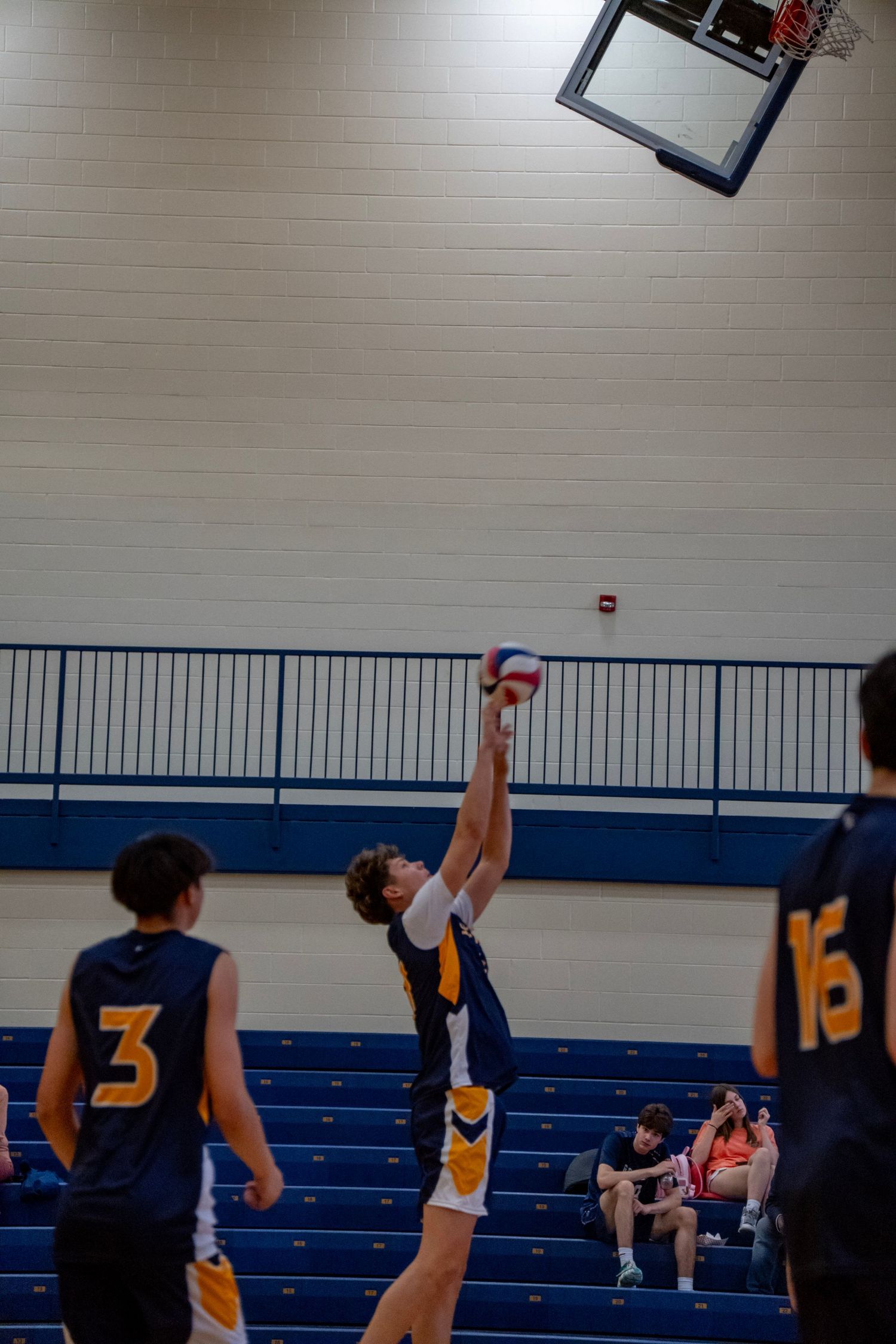 Volleyball players competing at the net with a reaching block attempt.
