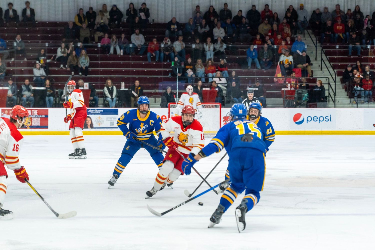 Hockey players battle for possession during a competitive match on the rink.