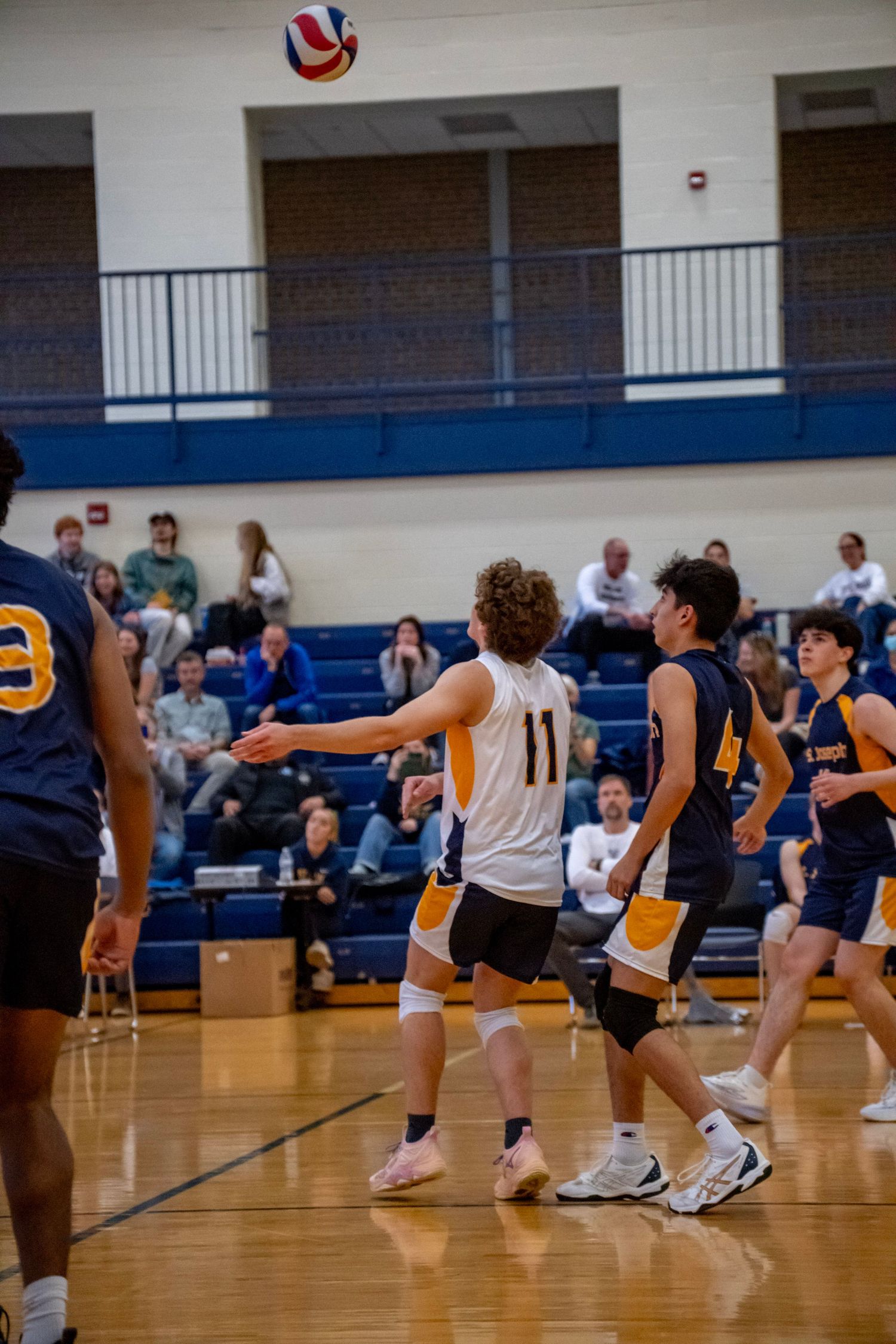 Volleyball players positioned on court watching ball during gameplay.