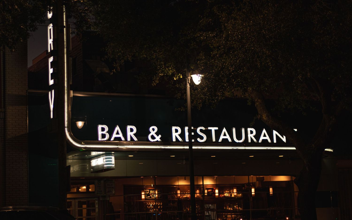 Vintage bar and restaurant sign illuminated at night with classic lettering.