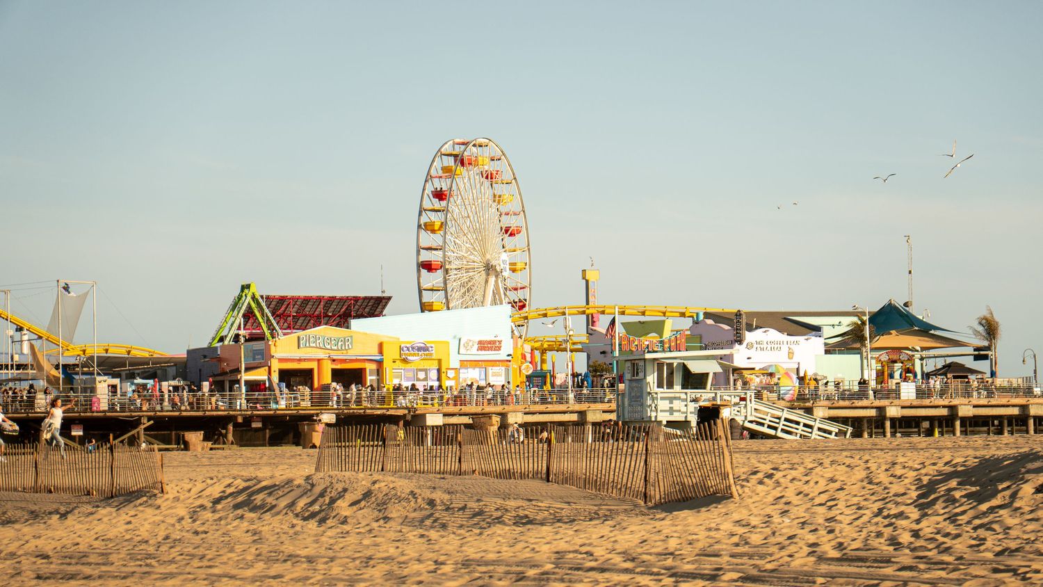 Santa Monica Pier amusement park with Ferris wheel and attractions on sandy beach.