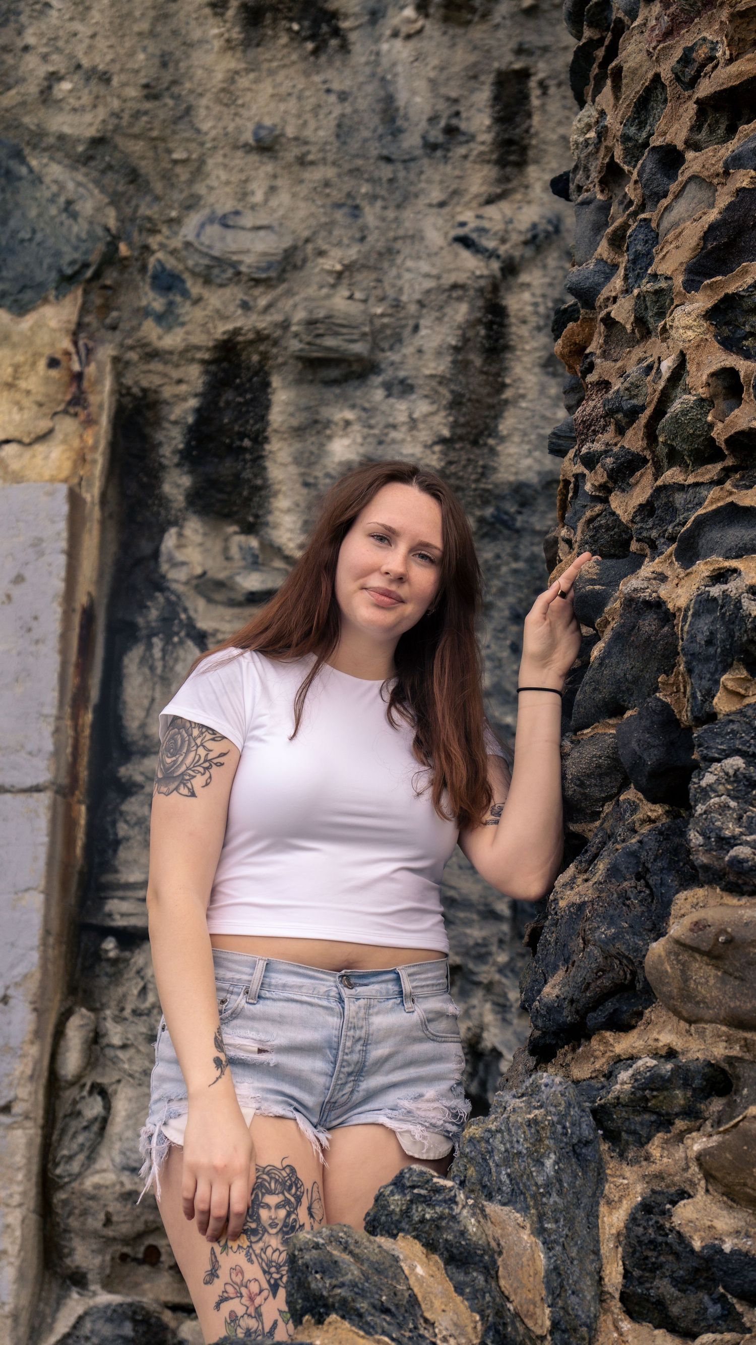 Lifestyle portrait session against textured stone wall highlighting casual summer style.
