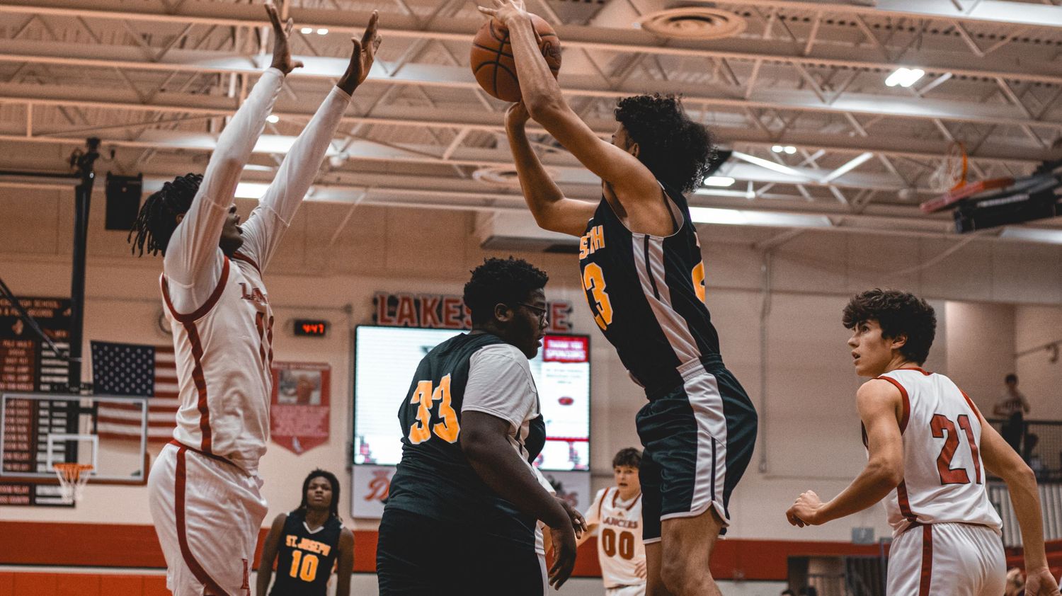 Panoramic view of a high school basketball game showing players and spectators in the gymnasium.