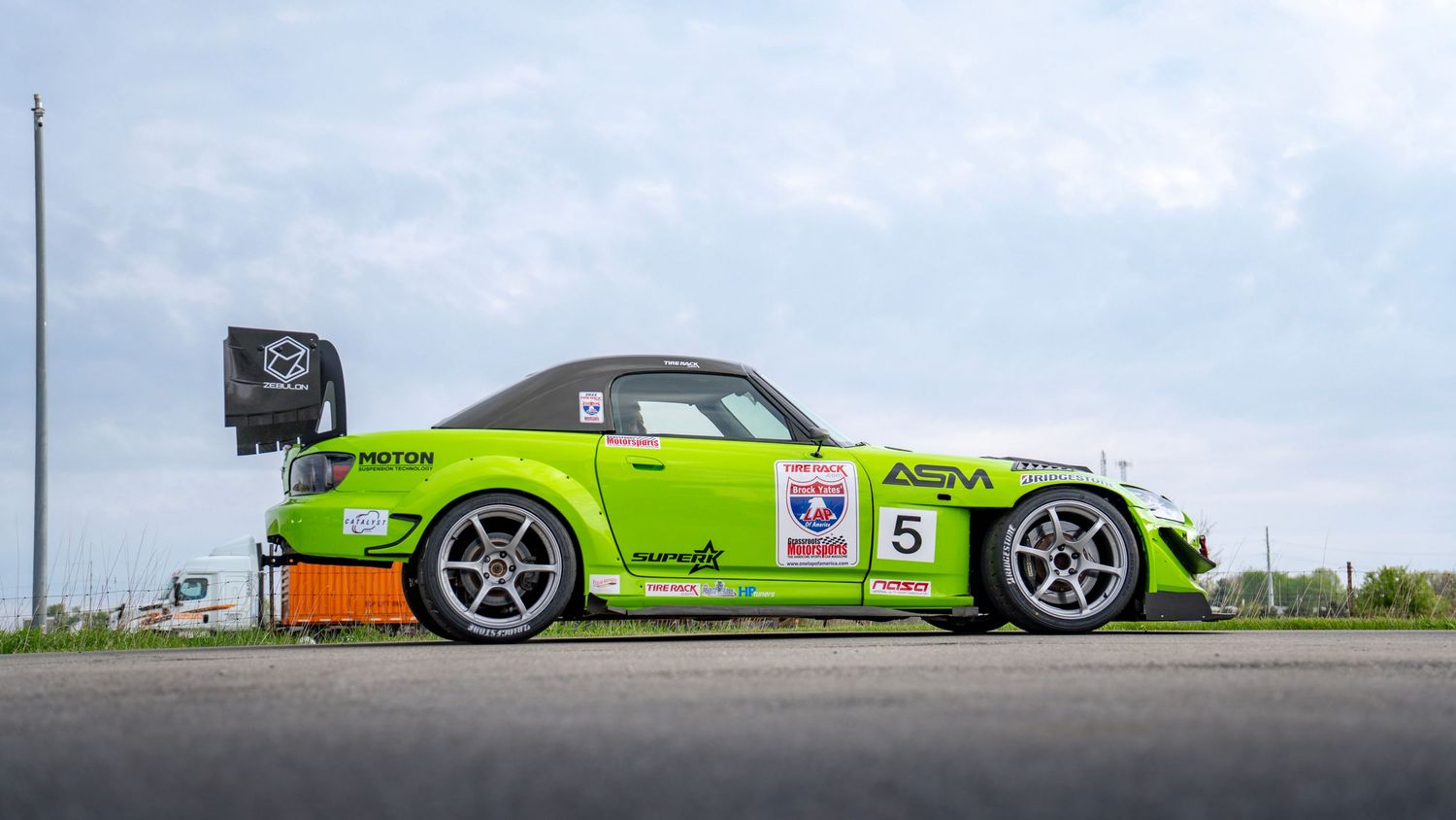 Low angle view of modified sports cars lined up against a bright blue sky.
