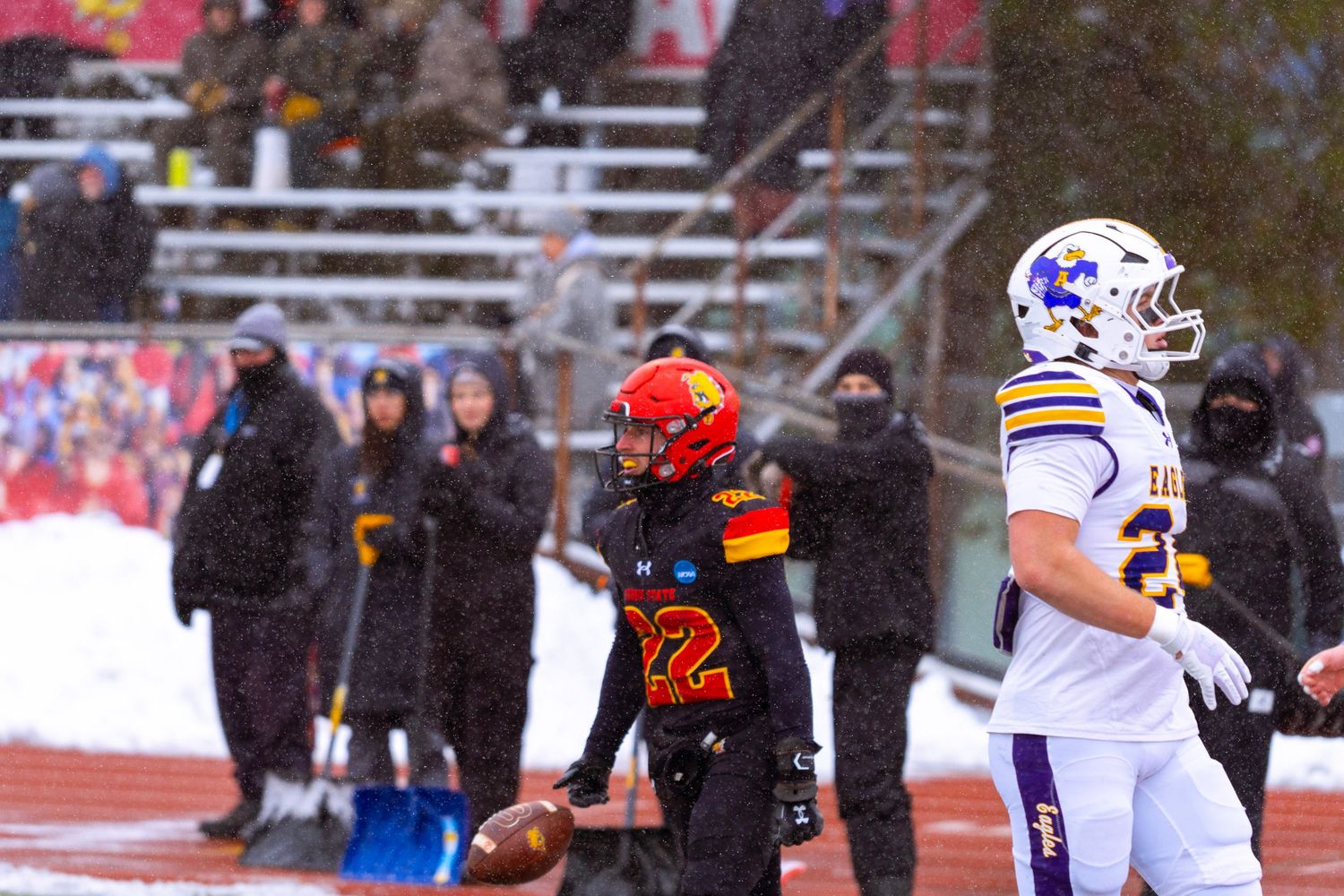 Football players from opposing teams in snowy conditions during a game with red and white team uniforms.