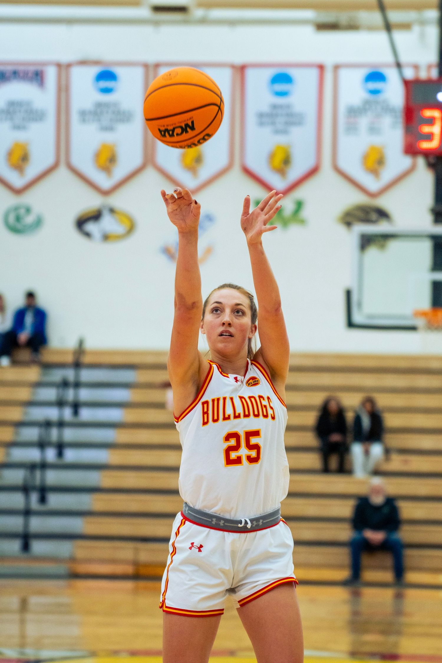 Basketball player in white Bulldogs jersey number 25 shoots a free throw during a game in a gymnasium.