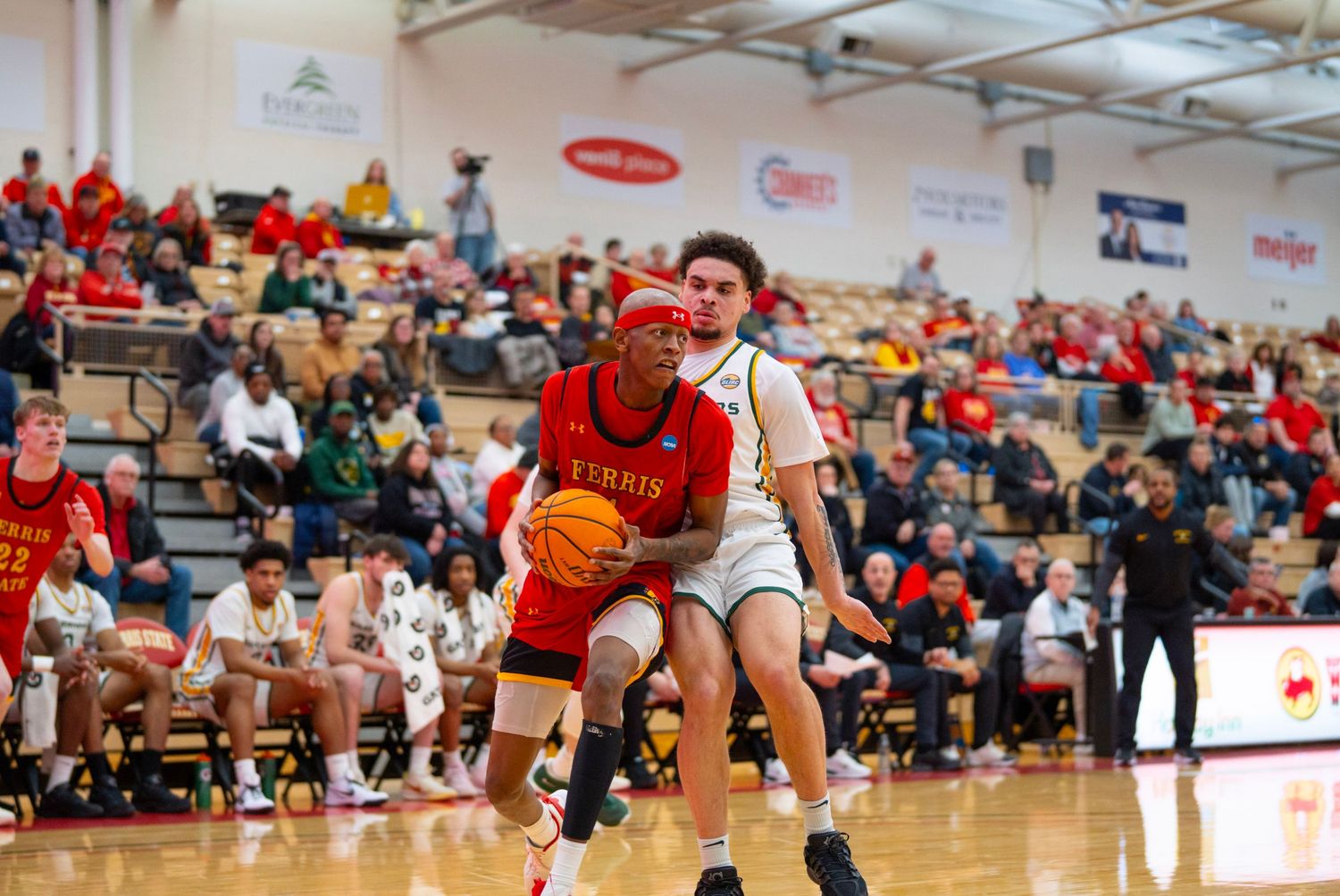 Basketball players compete intensely during a game in a crowded gymnasium with spectators watching from the stands.
